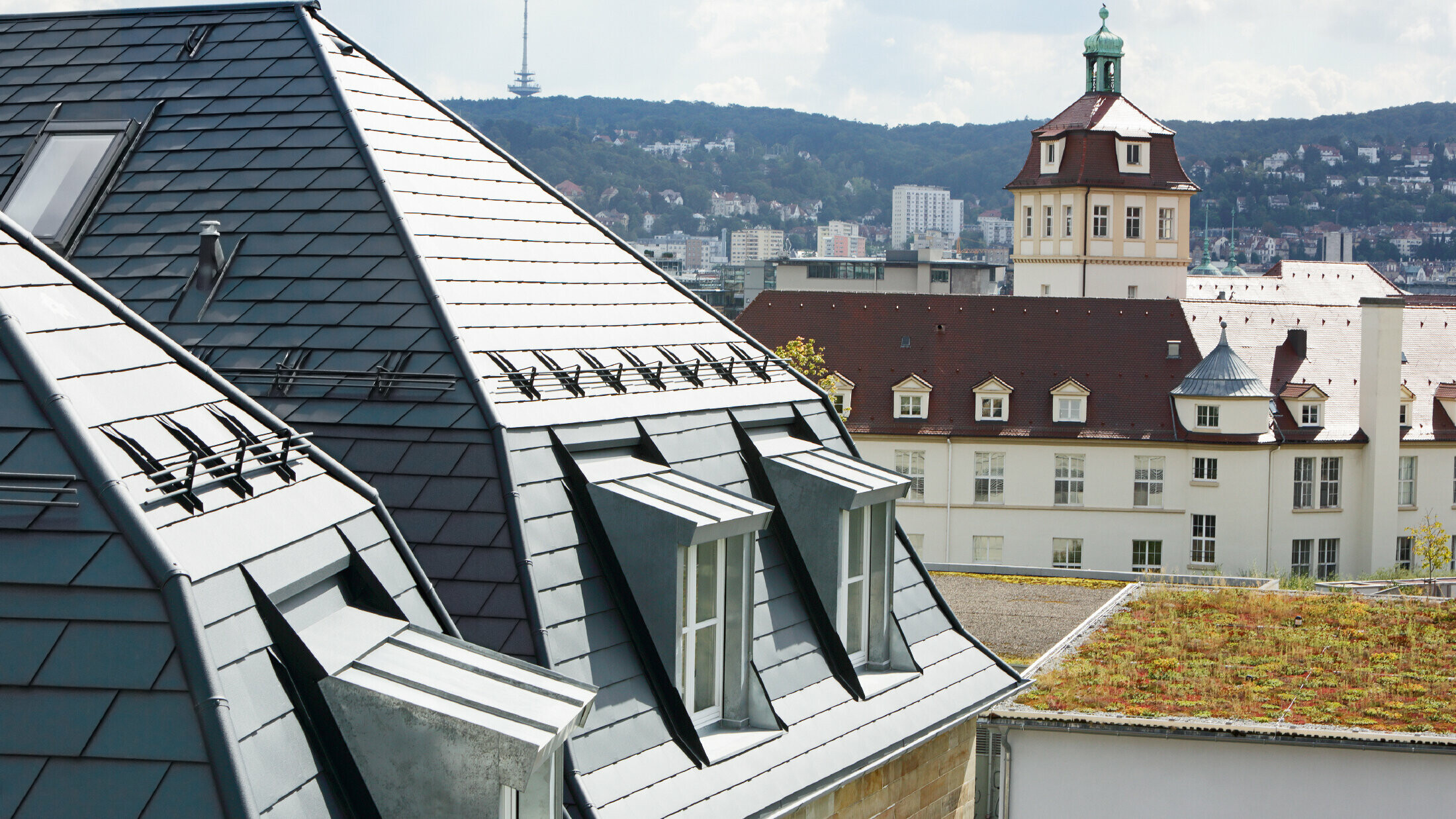 Starý mestský dom v Stuttgarte so zalomenou strechou a mnohými oknami vo vikieroch, pokrytá hliníkovým šindľom od spoločnosti PREFA vo farbe P.10 antracitová