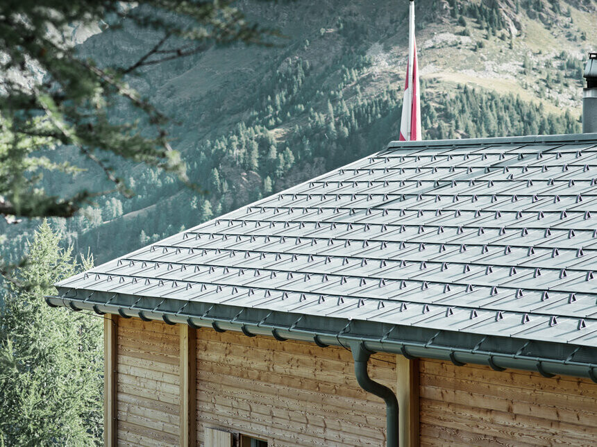 Švajčiarska chata pokrytá s PREFA falcovanou škridlou  a PREFA polkruhovým žľabom, ktorý je upevnený horným držiakom hliníkového žľabu