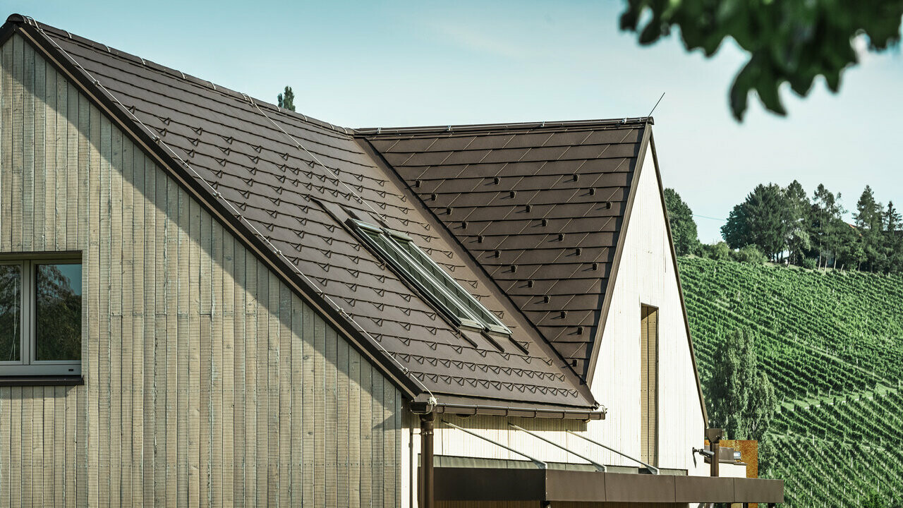 Rodinný dom s dvoma sedlovými strechami bol pokrytý s PREFA strešným šindľom vo farbe orieškovohnedá. Odvodnenie strechy je cez PREFA hranatý žľab. Fasáda je obložená so zvetraným drevom.