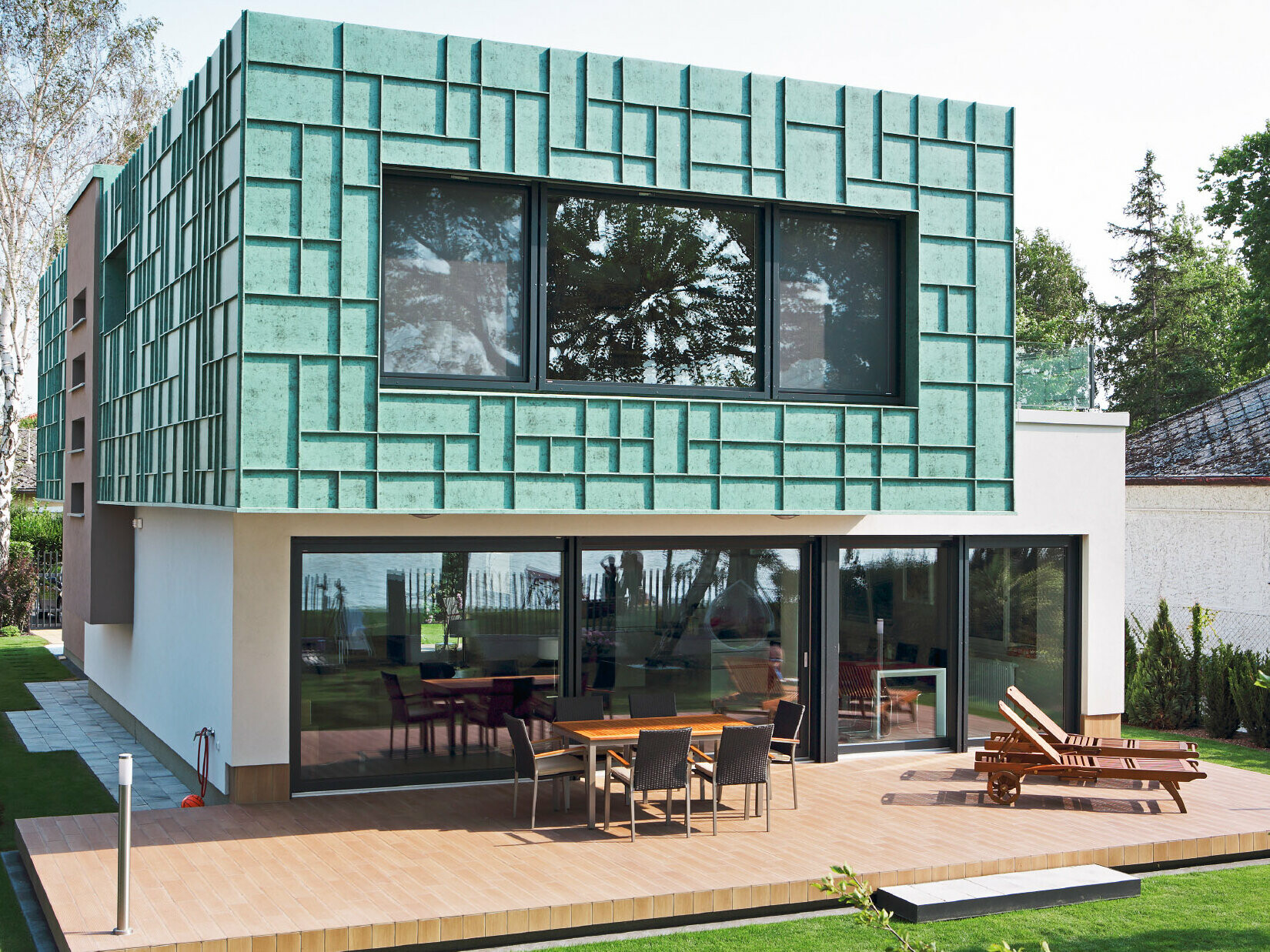Moderný rodinný dom s fasádou odolnou voči víchrici, ktorá bola obložená systémom PREFALZ vo farebnom odtieni P.10 patina zelená.