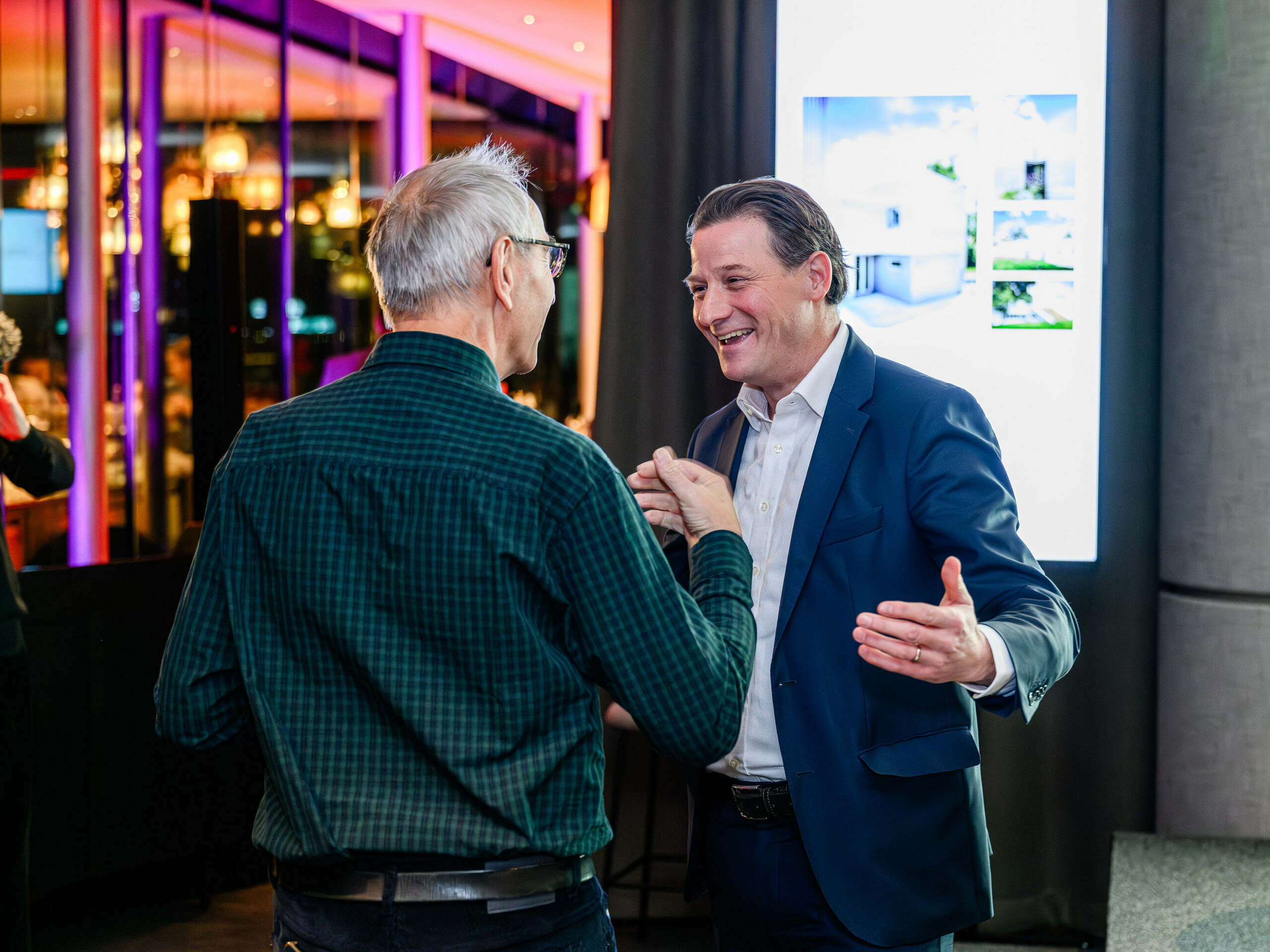 Srdečná diskusia na prezentácii PREFARENZEN 2026 v k47.wien: Leopold Pasquali, generálny riaditeľ spoločnosti PREFA, a Wolfgang Croce, ktorý fotografoval architektonické objekty PREFARENZEN, sa rozprávajú s opravdovým nadšením a vzájomným rešpektom. V pozadí je vidieť obrazovka s modernou architektúrou PREFA – silné dizajny z hliníka. Táto scéna symbolizuje sieťovanie medzi architektmi, projektantmi a spracovateľmi. PREFA spája ľudí, ktorí premýšľajú o architektúre novým spôsobom – s inovatívnymi produktmi z vysoko kvalitného plechu. Bol to večer plný výmeny názorov, inšpirácie a vízií budúcnosti.