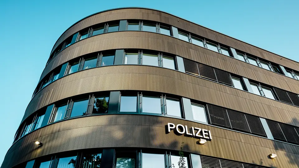Dramatický pohľad zospodu na zakrivenú novú budovu policajného komisariátu č. 43 v Hamburgu: Výrazná hliníková fasáda PREFA z eloxovaných extrudovaných profilov „Zacke“ v odtieni strednej bronzy priťahuje ako architektonický magnet všetky pohľady. Jemná, rytmická štruktúra vytvára dynamické prechody svetla a tieňa a zdôrazňuje plynulé zaoblenia budovy. Hliník PREFA presviedča vysokou odolnosťou voči poveternostným vplyvom, ochranou proti korózii a dlhou životnosťou – ide o udržateľné riešenie s nízkymi nárokmi na údržbu pre precíznu, modernú fasádnu architektúru.