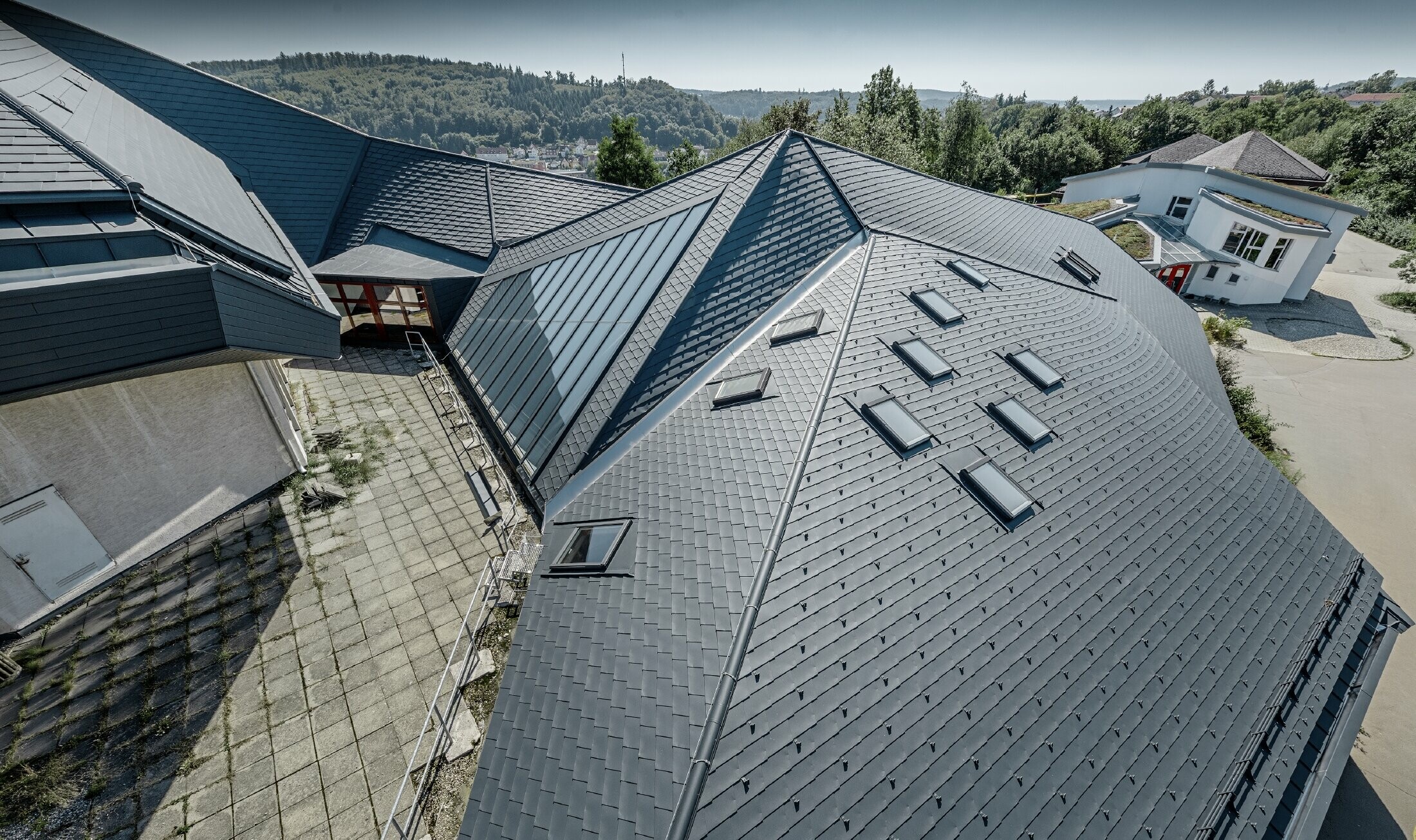 Waldorfská škola v Heidenheime s novo zrekonštruovanou strechou, veľká strešná plocha, tvarovo veľmi členitá bola pokrytá strešným šindľom PREFA v antracitovej