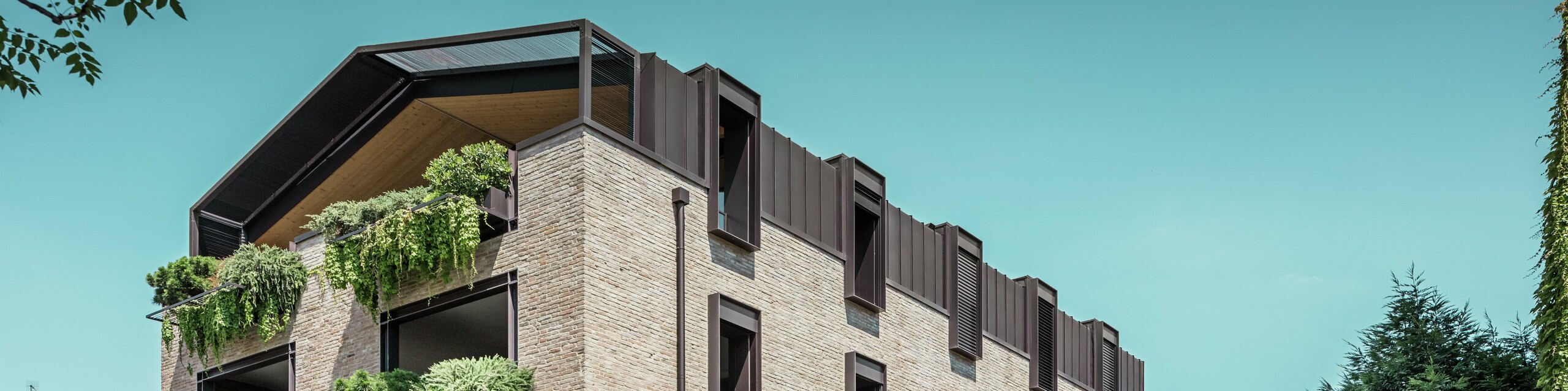 Moderná obytná budova v Taliansku s hliníkovou strechou PREFALZ v odtieni P.10 orieškovohnedá, tehlovou fasádou a visutými záhradami – udržateľná architektúra pre renováciu tejto budovy.