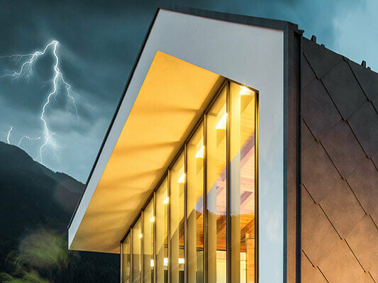 Aufnahme eines modernen Hauses ohne Dachvorsprung mit Unwetter im Hintergrund mit Blitz