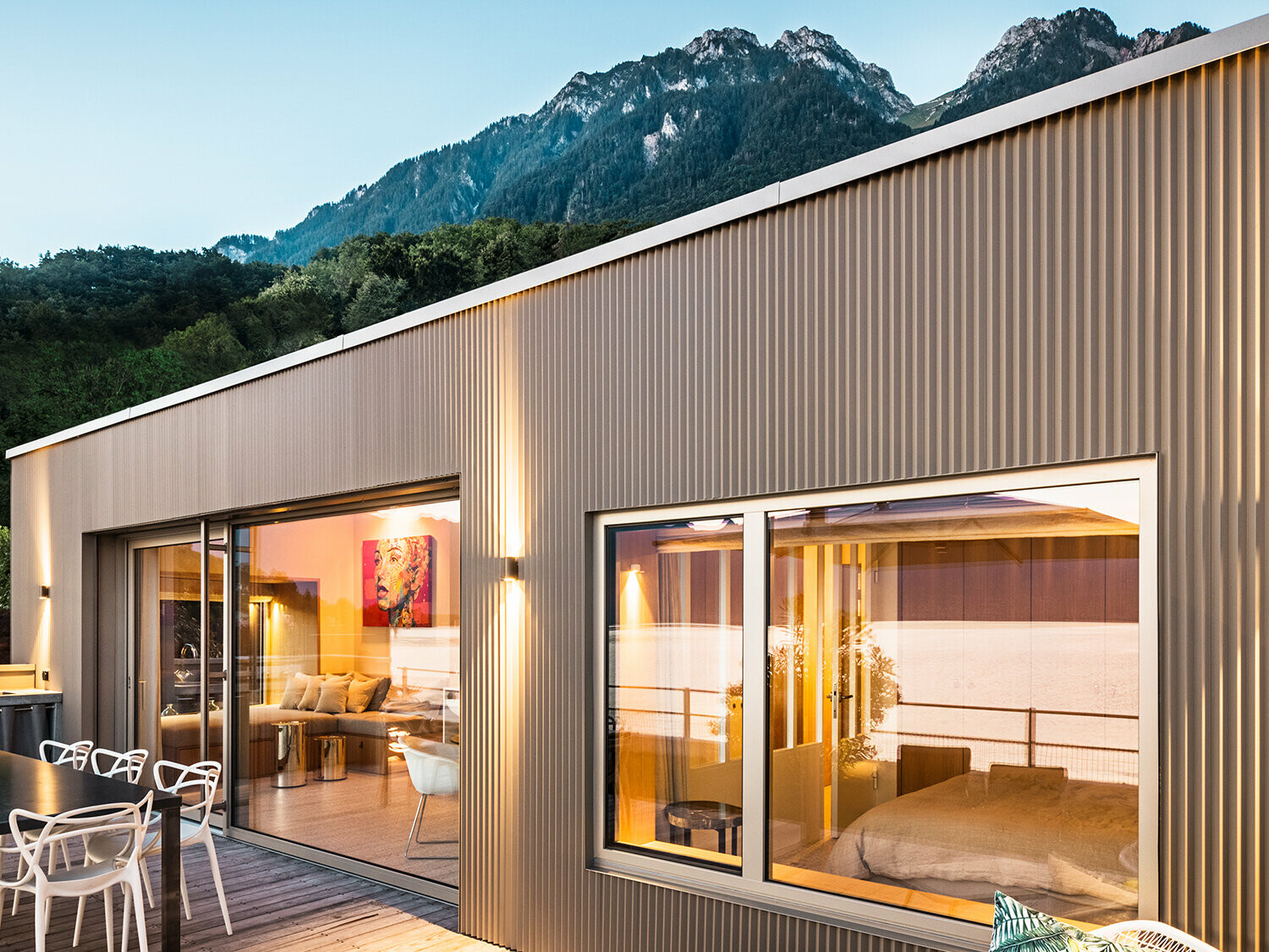 Pohľad na terasu a časť vnútra budovy večer.