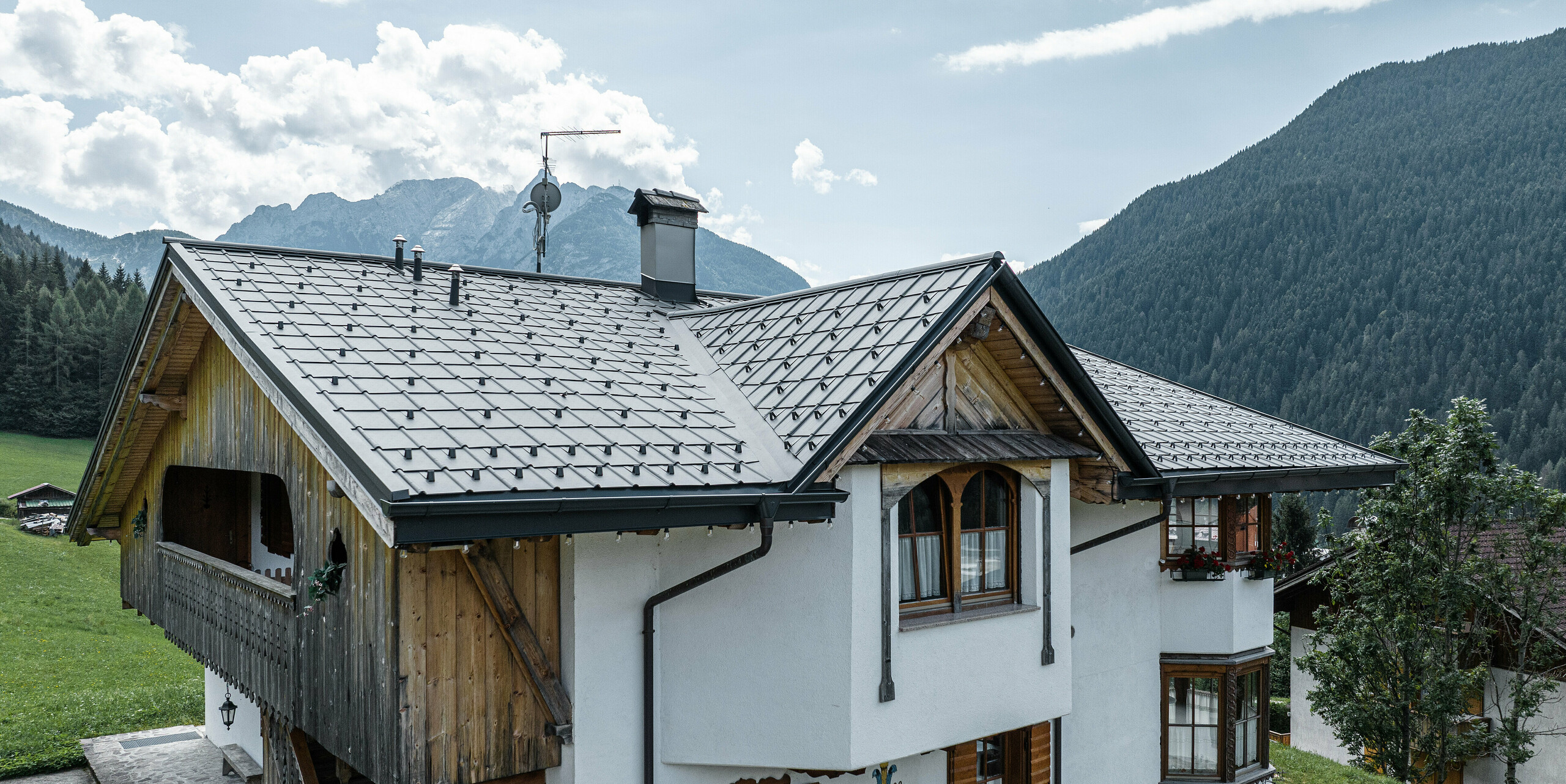 Horská chata v Auronzo di Cadore v Taliansku s čerstvo zrekonštruovanou strechou zo svetlošedých škridiel PREFA, ktoré spájajú tradíciu a modernosť. Starostlivá rekonštrukcia zachováva očarujúce detaily, ako sú drevené balkóny a rezbárske práce, a zároveň chráni budovu odolnou hliníkovou strechou nenáročnou na údržbu, ktorá zapadá do prírodnej horskej krajiny.