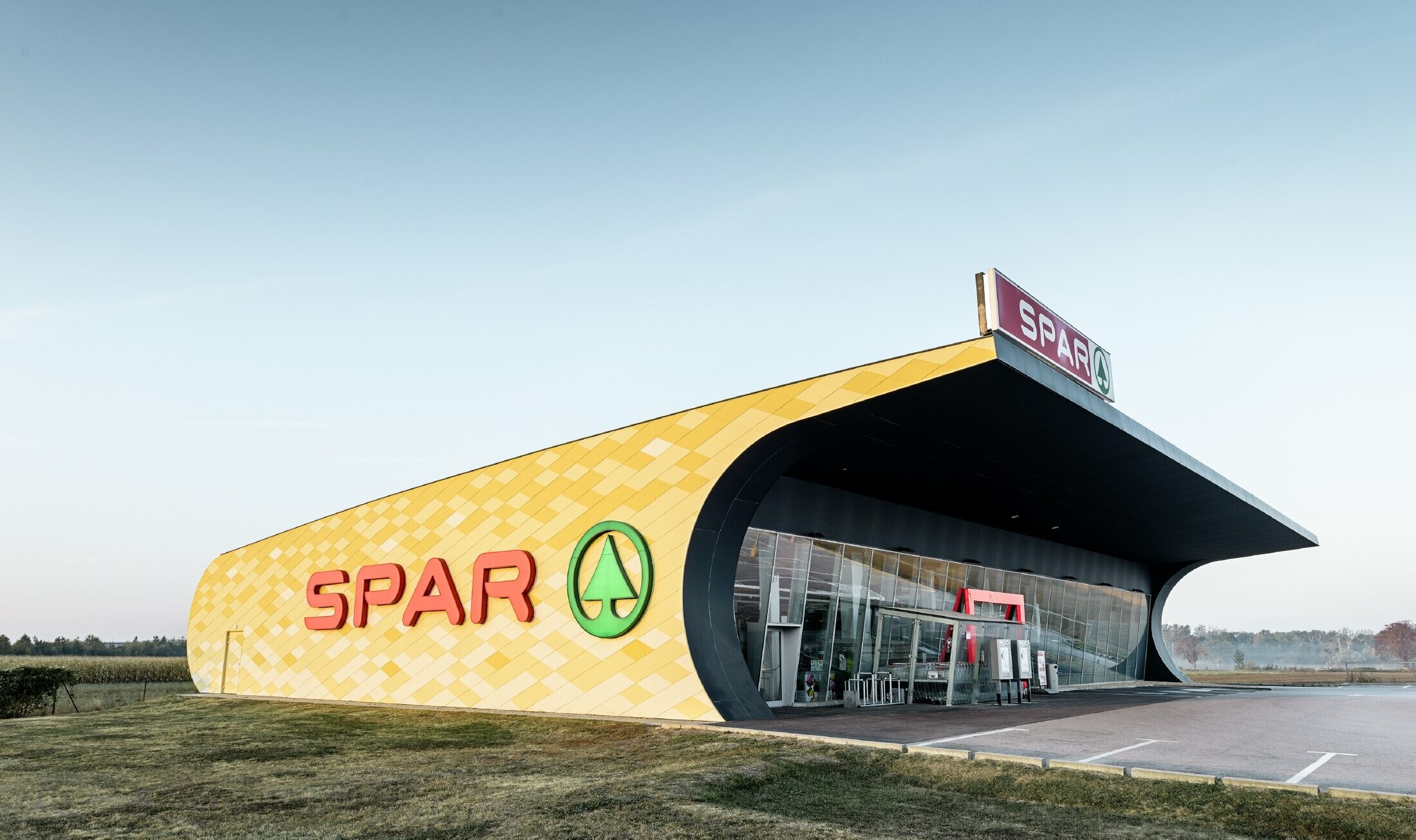 Predajňa obchodného reťazca Spar s hliníkovou fasádou v žltooranžovom károvanom dizajne s logom Spar