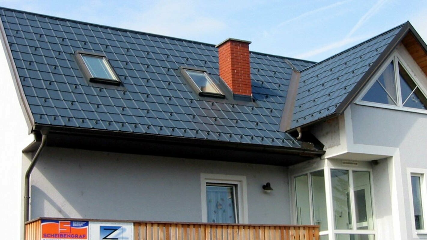 Rodinný dom s modrou fasádou so sedlovou strechou nedávno zrekonštruovanou s použitím produktov PREFA.