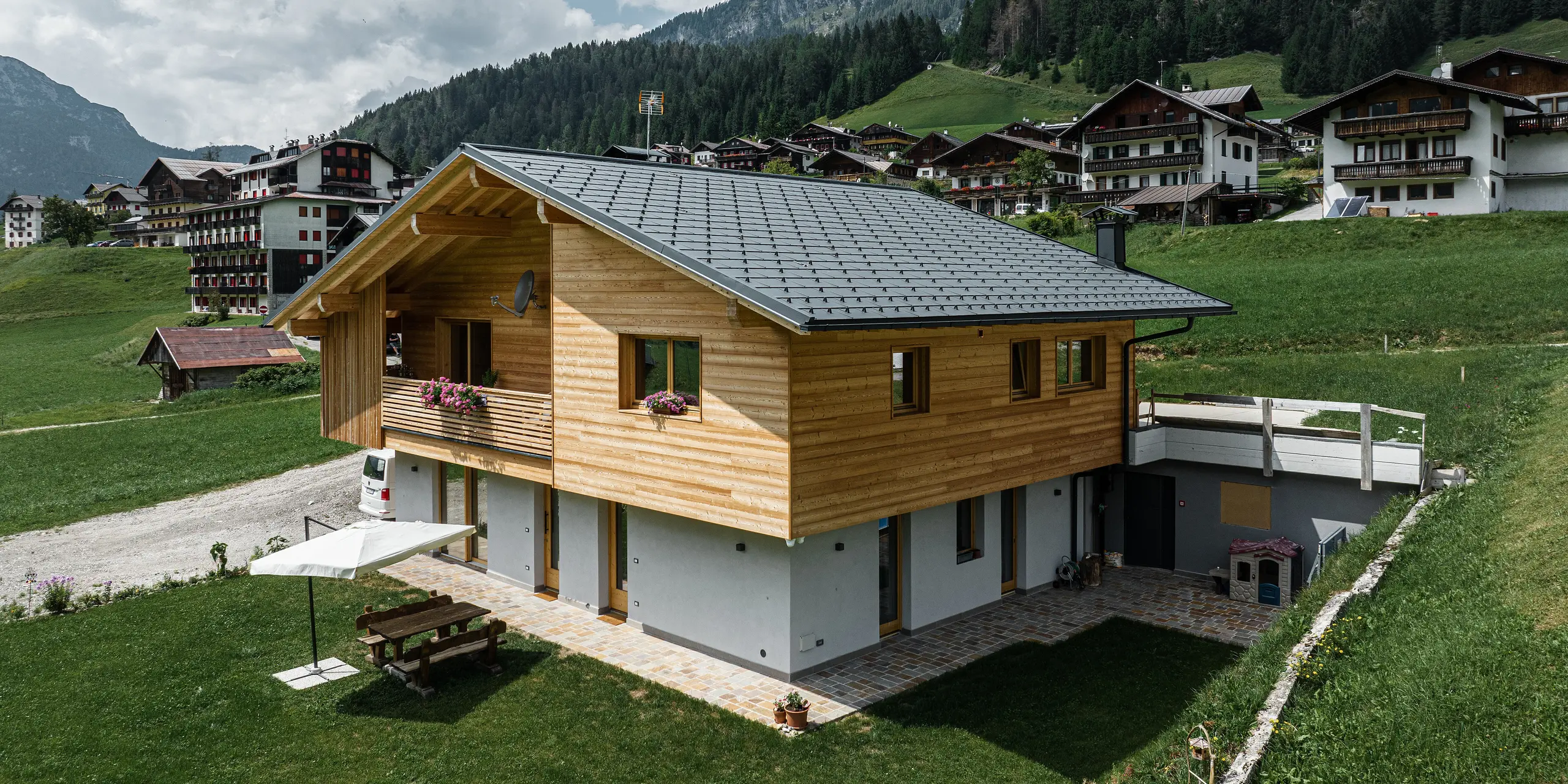 Rodinný dom Casa Hoffe v alpskej komunite Sappada v Taliansku ukazuje harmonickú súhru tradičnej a modernej architektúry. Vybavené strešnými panelmi PREFA R.16 v čiernej farbe P.10, ktoré poskytujú stabilitu a eleganciu, zatiaľ čo fasádne panely Siding.X vo vstupnej časti obohacujú dizajn o extravagantný nádych. Odolné hliníkové prvky PREFA sa bez problémov integrujú do drevenej fasády typickej pre tento región a ponúkajú trvalú ochranu uprostred idylickej horskej krajiny.