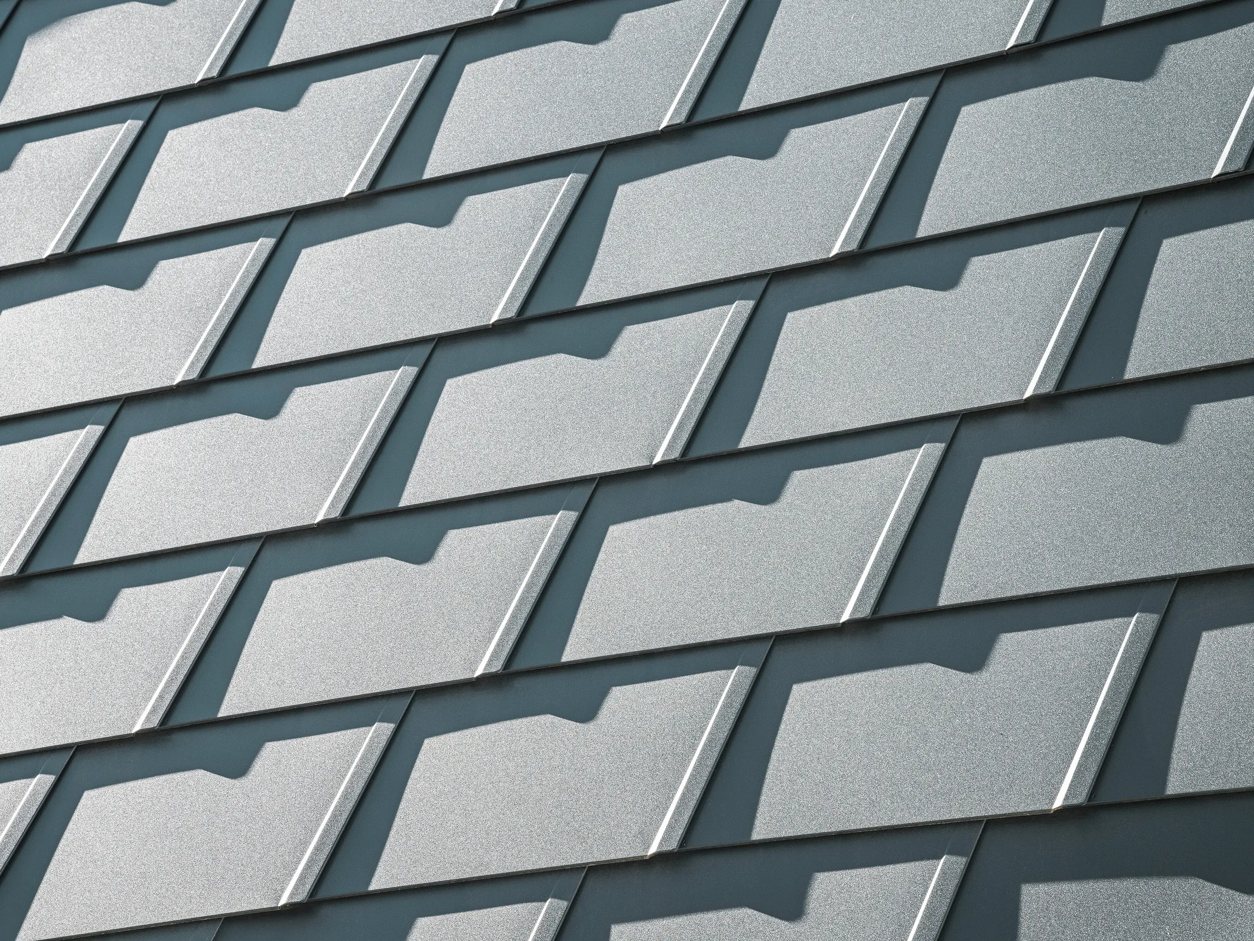 Detailný pohľad na strešné šindle PREFA DS.19 v antracitovej farbe P.10 na rodinnom dome v Mechernichu. Odolné hliníkové strešné šindle poskytujú optimálnu ochranu pred poveternostnými vplyvmi a zabezpečujú moderný, estetický dizajn strechy.