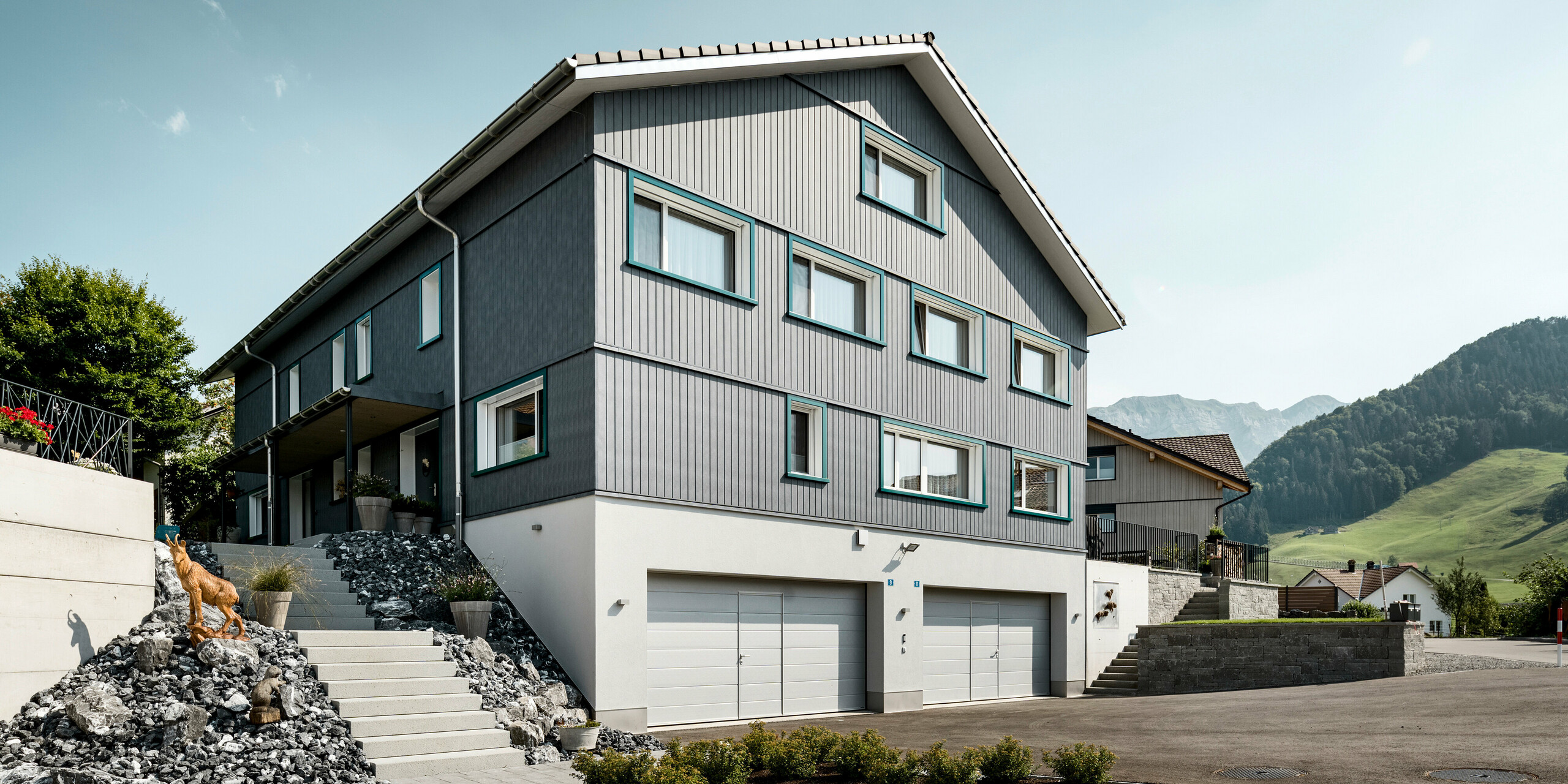 PREFA Siding vo farbe P.10 kamenná šedá a P.10 prefa biela na fasádach dvoch susedných bytových domov vo Weissbad vo Švajčiarsku.