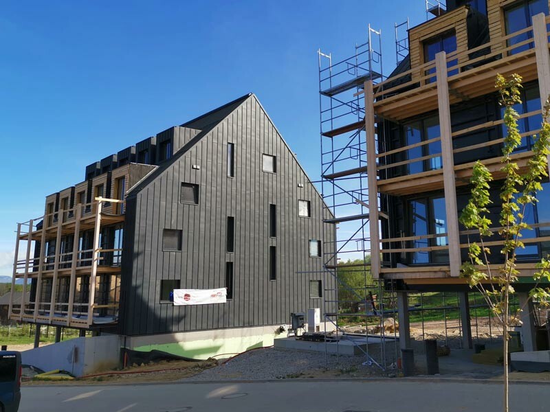 Hotová fasáda prefalz na slnku s plachtou s rozostavanou druhou budovou.