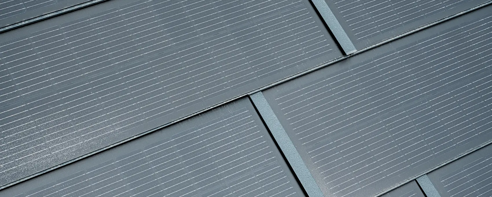 Detailný záber na položený malý integrovaný solárny panel. Malý integrovaný solárny panel vo farbe P.10 antracitová bol kombinovaný so strešným panelom R.16. 