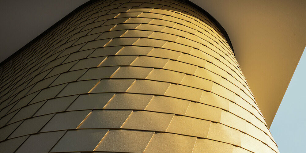 Detailný pohľad na zakrivené obloženie fasády s PREFA fasádnym šindľom vo farbe mayská zlatá