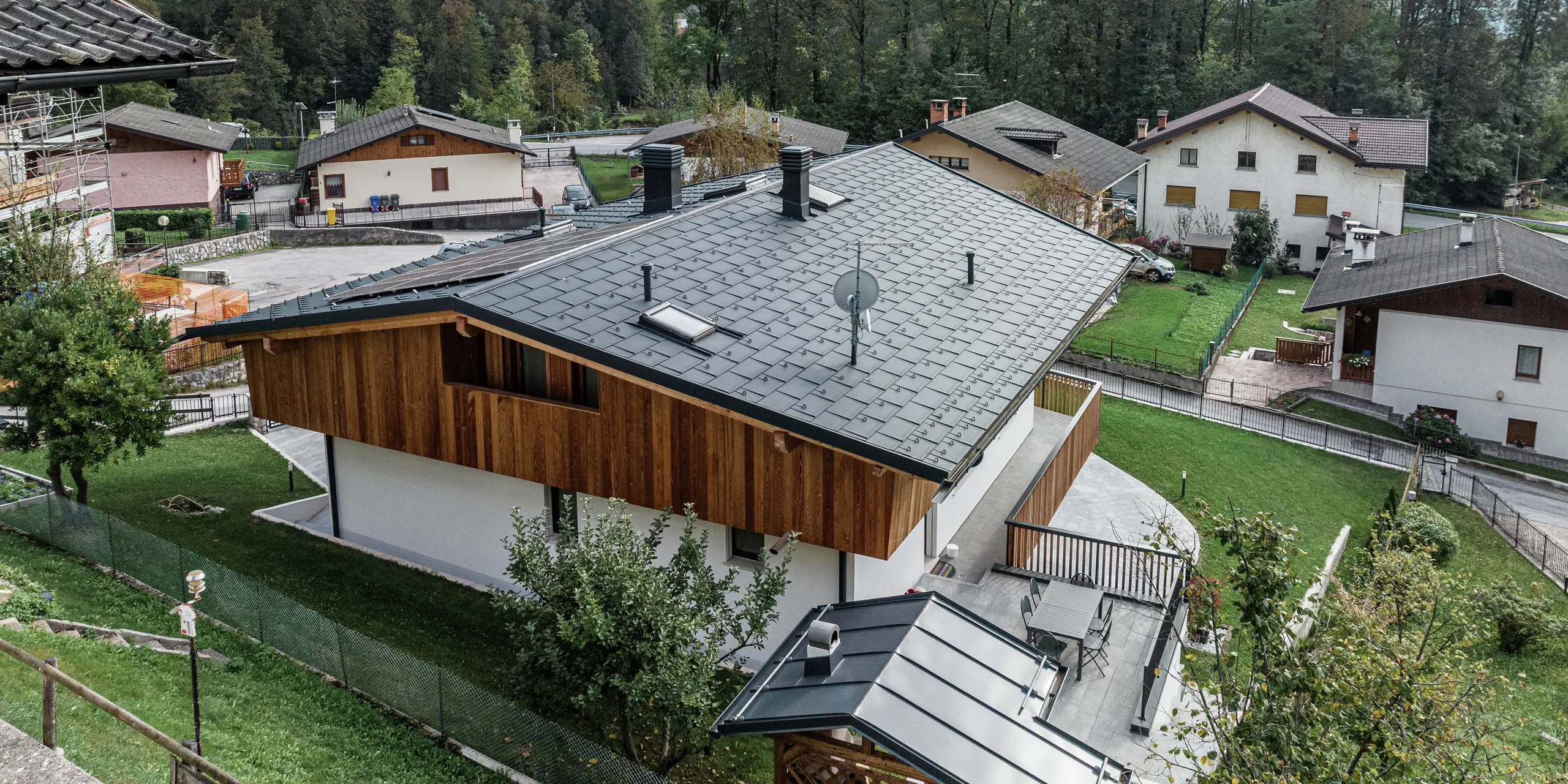 Zrekonštruovaný rodinný dom v Agorde v Taliansku s odolnou hliníkovou strechou. Strešný panel PREFA R.16 vo farbe P.10 antracit poskytuje optimálnu ochranu pred poveternostnými vplyvmi a harmonicky zapadá do okolia. Strešný odvodňovací systém PREFA s hranatým žľabom a odvodňovacou rúrou zabezpečuje účinný odtok vody. Kombinácia prírodnej drevenej fasády na hornom podlaží, bielej omietnutej fasády na prízemí a vysokokvalitného hliníka v oblasti strechy dodáva budove štýlový a moderný vzhľad.