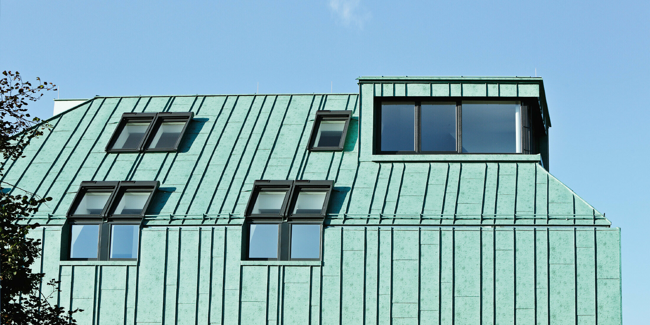 Riešenie strechy a fasády so systémom PREFALZ vo farbe patina zelená od spoločnosti PREFA s rôznymi šírkami pásov