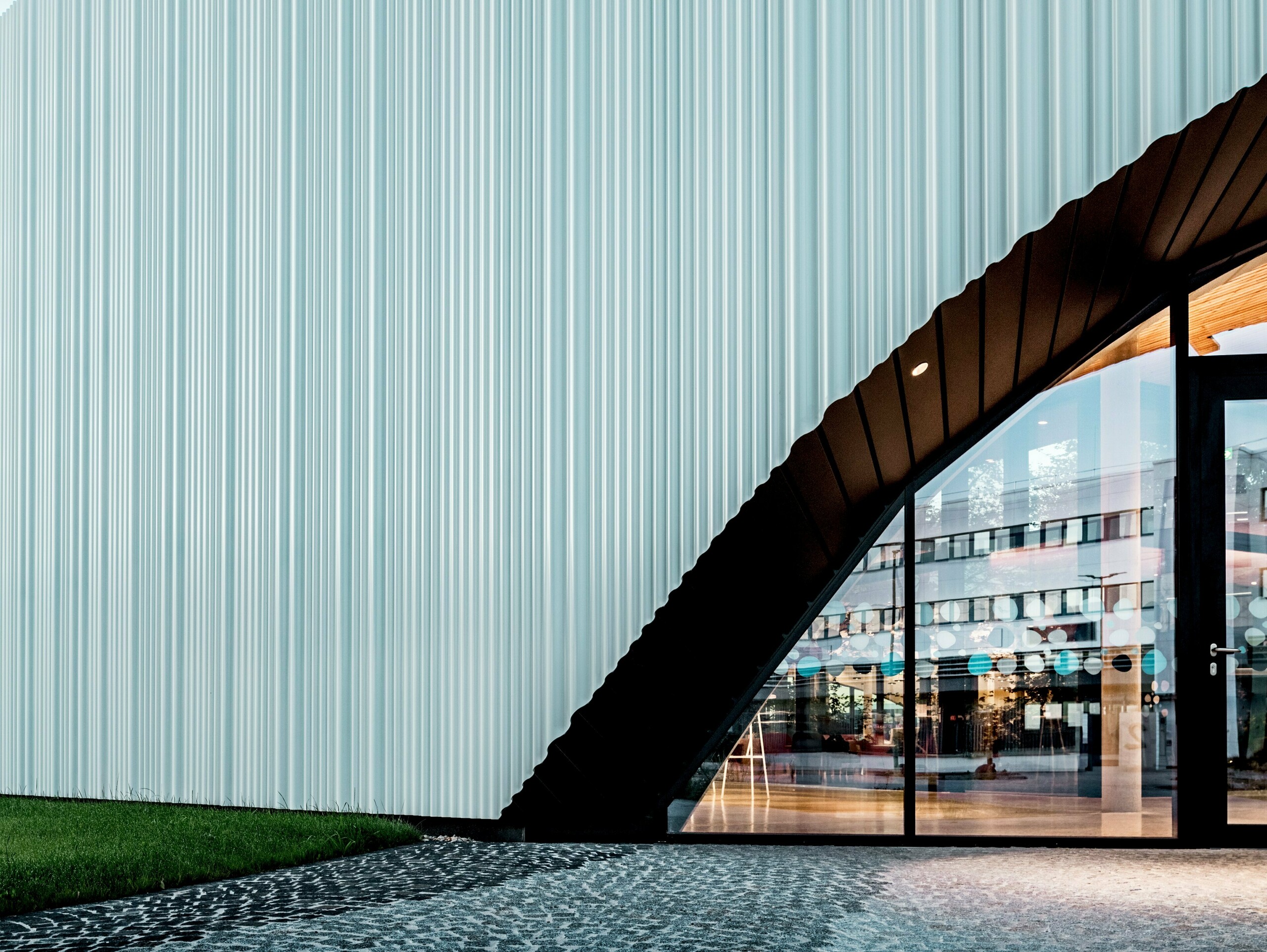 Špektakulárny dizajn fasády s vlnitým profilom PREFA z vysoko kvalitného hliníka zdobí budovu spoločnosti LKW Walter vo Viedni. Jemne zakrivená vertikálna štruktúra profilov vytvára elegantný vlnitý vzor, ktorý vytvára fascinujúce hry svetla. Kým moderná budova zaujme jasným dizajnom, zakrivený výrez fasády vytvára výrazný architektonický kontrast. Odolné a koróziivzdorné hliníkové profily so skrytým upevnením zaisťujú vysokú kvalitu a bezúdržbový vonkajší plášť.