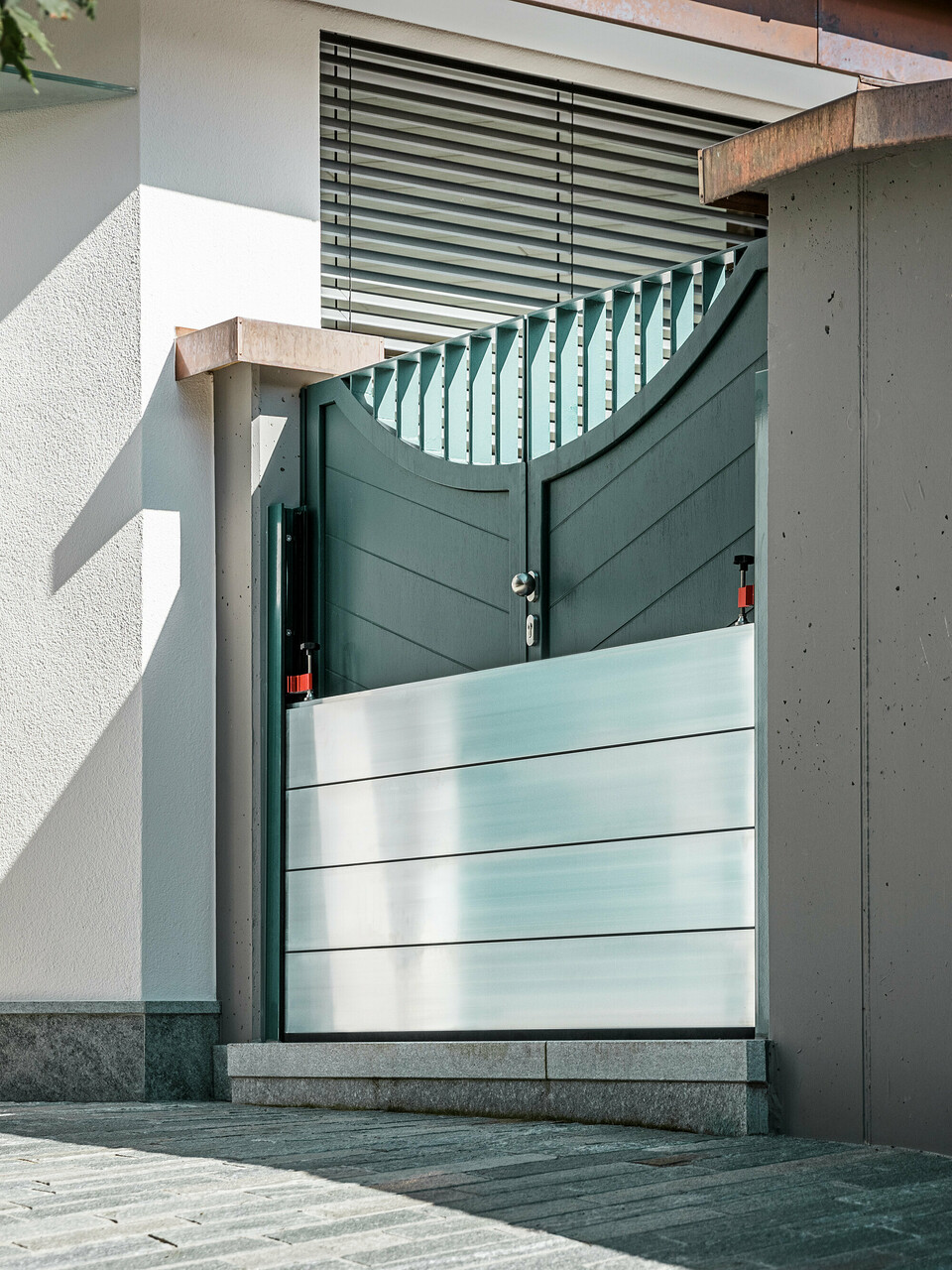 Nahaufnahme eines montierten PREFA Hochwasserschutzsystems am Gartentor eines Einfamilienhauses in Schwaz, Tirol. Die eingesetzten Dammbalken aus Aluminium sind in seitlich angebrachte Befestigungsprofile eingeschoben und schützen den Eingangsbereich zuverlässig vor eindringendem Wasser. Das System überzeugt durch seine schlichte Optik, die schnelle Einsatzbereitschaft und die korrosionsbeständigen Materialien - ideal für den privaten Objektschutz. Die Wandprofile sind in der gleichen Farbe wie die Tür gehalten, so dass ein harmonischer Gesamteindruck entsteht.