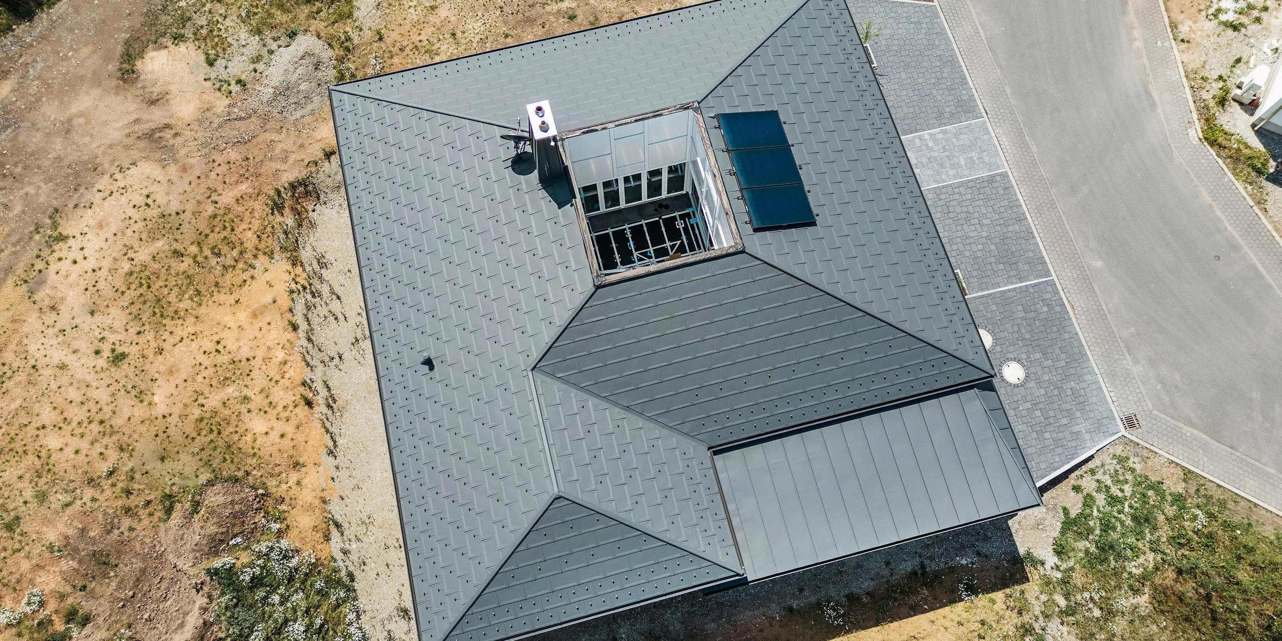 Strešný panel PREFA R.16 a PREFALZ ako aj dažďový zvod a polkruhový žľab P.10 tmavošedá na streche bungalovu