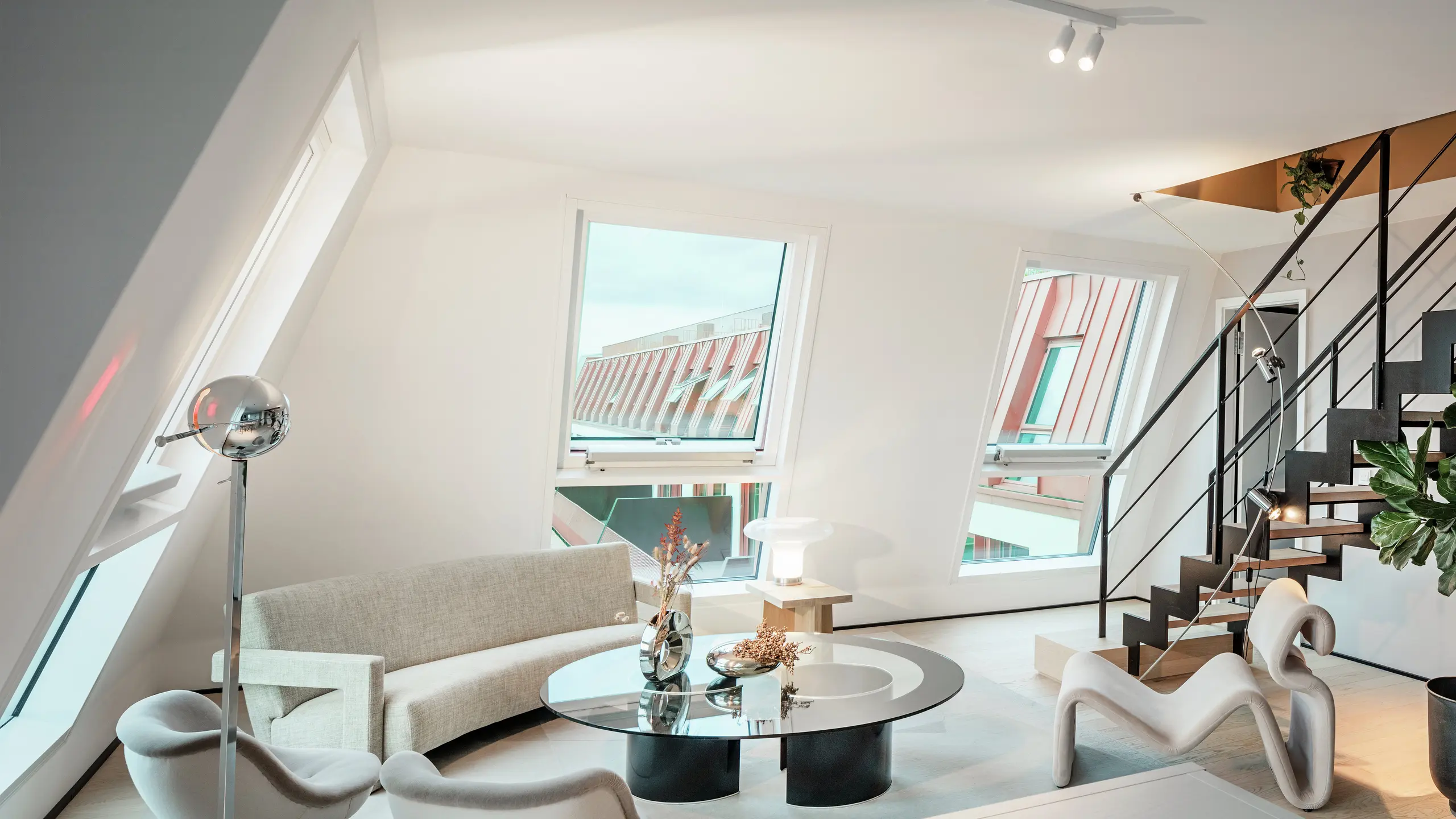 Pohľad do interiéru svetlého penthousu v rezidenčnom projekte Van B v Mníchove s pohľadom na vysokokvalitnú hliníkovú strechu PREFALZ v špeciálnej farbe IGP Orange HDP. Veľké okná prepúšťajú dostatok denného svetla a zdôrazňujú moderný koncept bývania. Jasné línie, dizajnový nábytok a precízne spracovanie strešných spojov ukazujú, ako sa dá kvalitná a štýlová architektúra realizovať nielen zvonka, ale aj zvnútra.