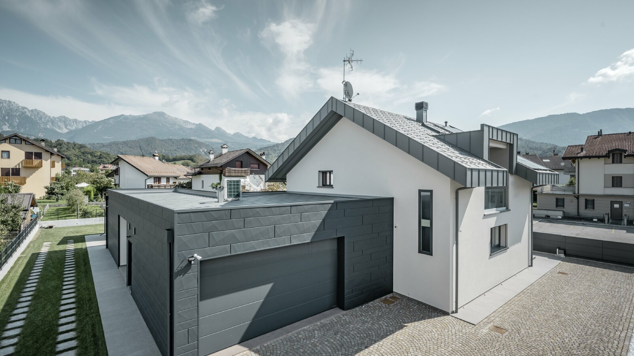 Foto vom Einfamilienhaus, die Garage ist mit Siding.X gedeckt, das Dach ist in R.16 in der Farbe P.10 hellgrau gedeckt.