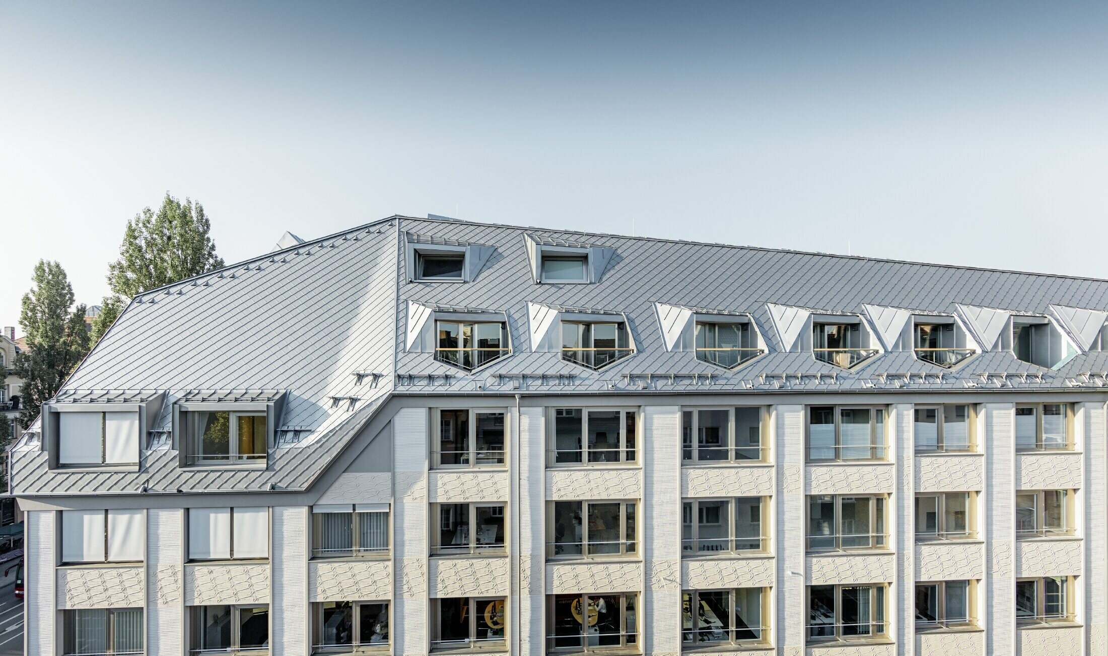 Zrekonštruované manzardové byty s priestrannou otvorenou galériou v rezidenčnej a obchodnej budove na rohu Leopoldstraße a Hohenzollernstraße v Mníchove so strešnou krytinou PREFA šablóna