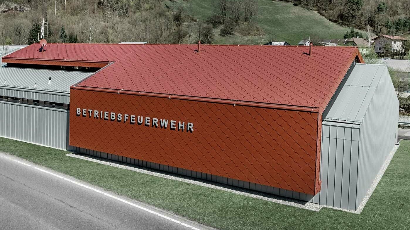 Das neue Feuerwehrhaus der Betriebsfeuerwehr der Firmen PREFA und Neuman Aluminium wurde mit der neuen Dach- und Wandraute 44 × 44 in P.10 Oxydrot sowie Prefalz in Silbermetallic verkleidet.