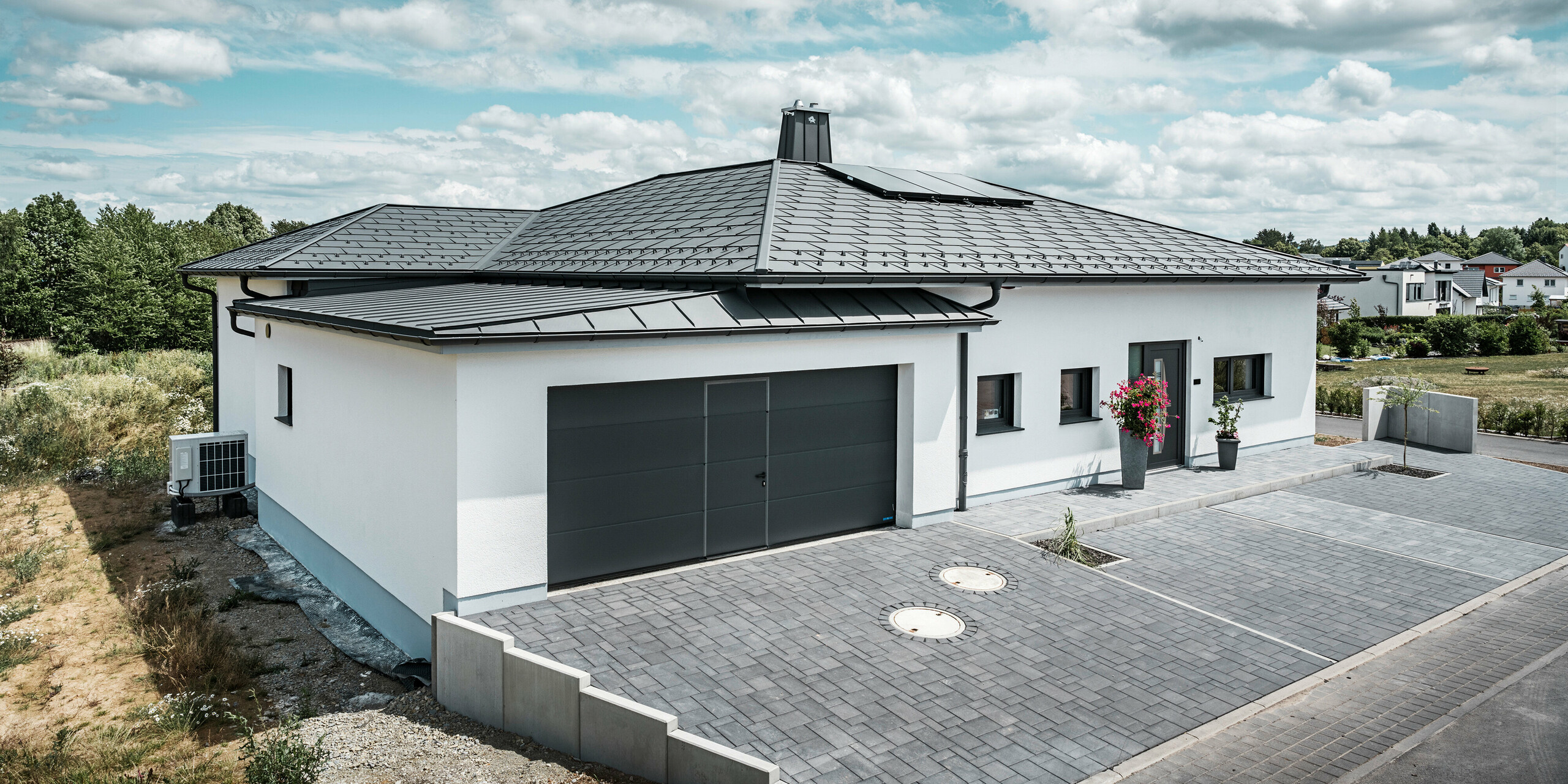 Strešný panel PREFA R.16 a PREFALZ ako aj dažďový zvod a polkruhový žľab P.10 tmavošedá na streche bungalovu