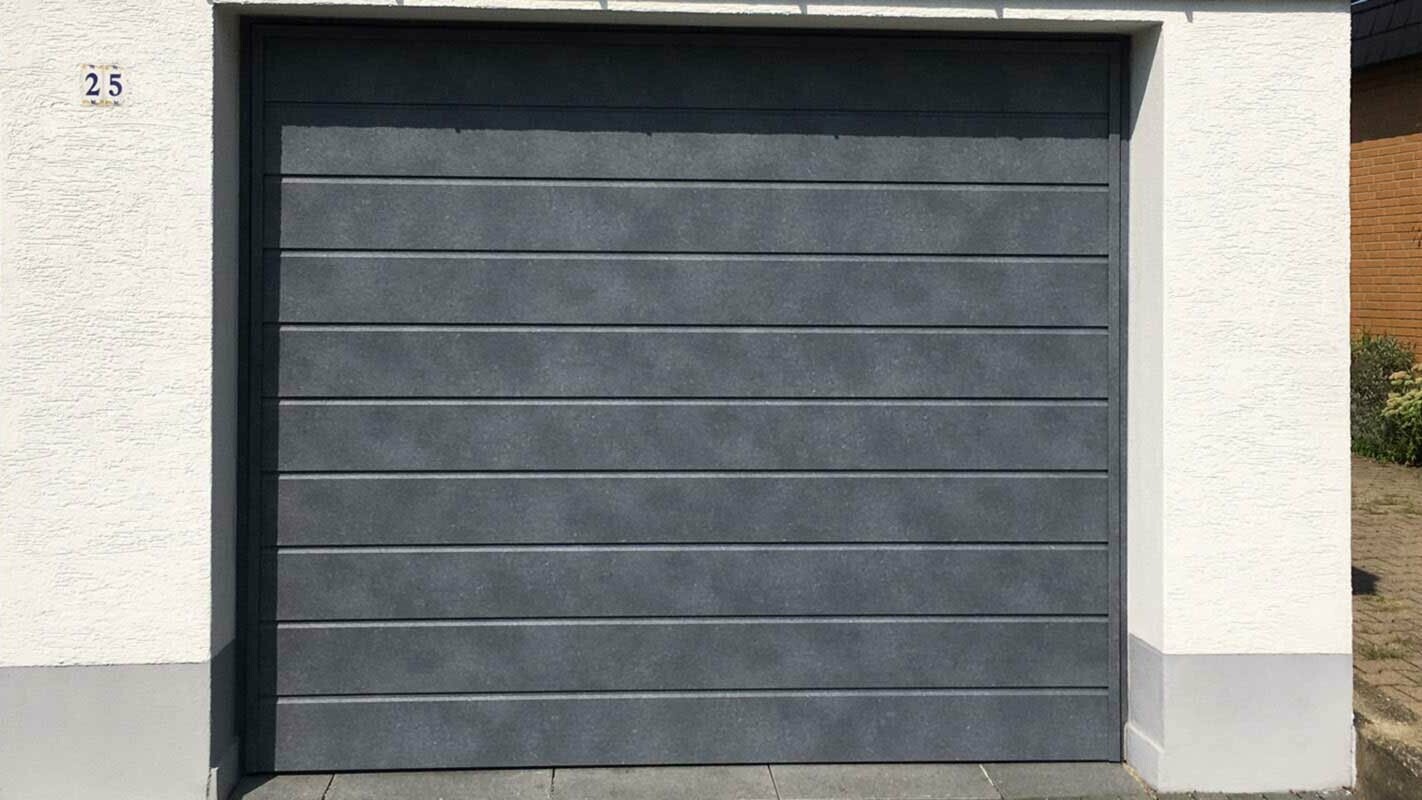 Garážová brána obložená horizontálne montovanými PREFA Sidings vo farbe kamenná šedá 