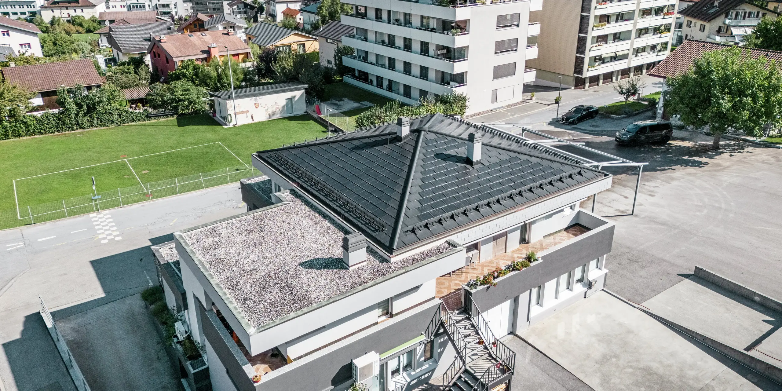 Moderná stanová strecha vinárstva Leukersonne v Sustene (CH) s integrovaným solárnym panelom PREFA a strešným panelom R.16 v čiernej farbe P.10 - odolným voči poveternostným vplyvom a energeticky účinným.