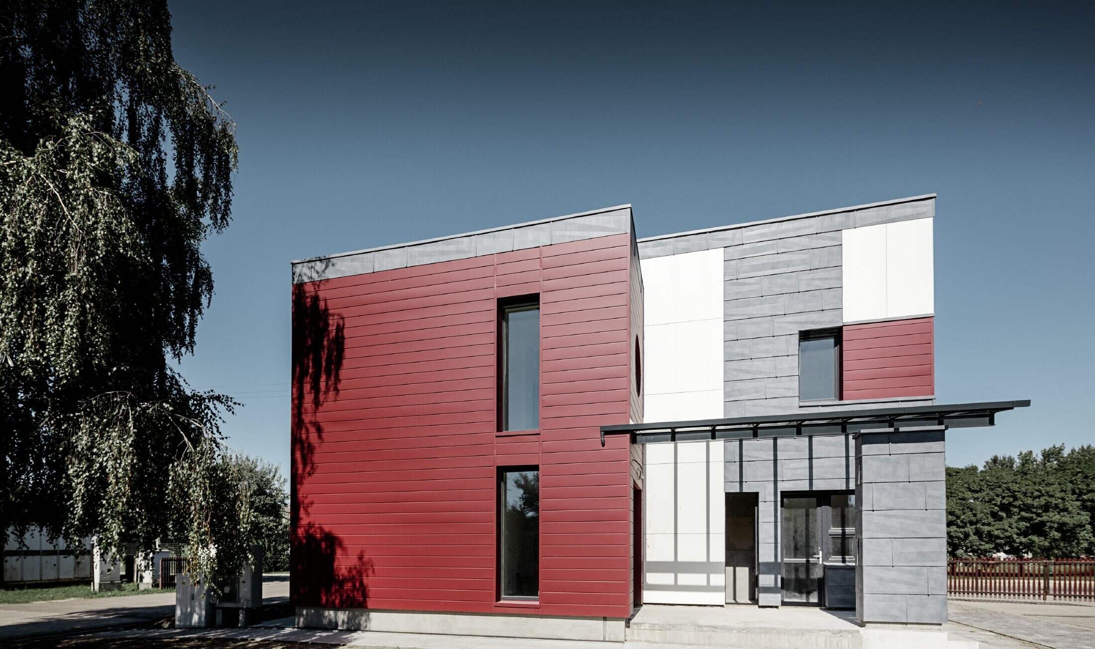 Moderná kancelárska budova s delenou hliníkovou fasádou vytvorenou z PREFA Siding v červenej, kamennošedej a bielej farbe, z PREFA fasádneho panelu FX.12 a z PREFA hliníkového kompozitného panela