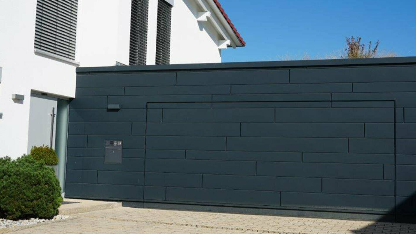 Fasáda garáže po rekonštrukcii s použitím PREFA Sidings antracitovej farby, garážová brána je namontovaná v jednej rovine s fasádou 