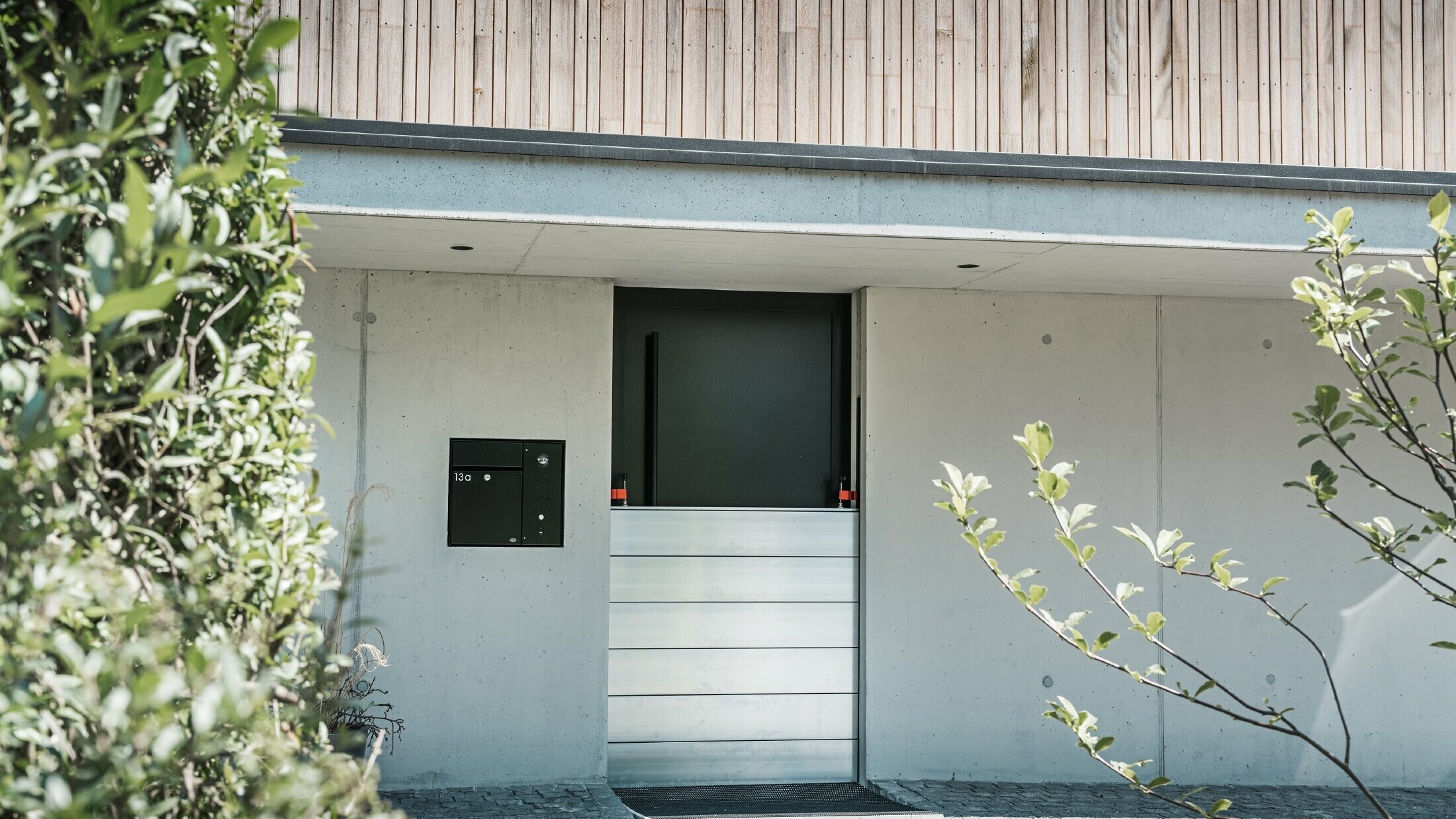 Pred vstupnými dverami rodinného domu s drevenou fasádou je nainštalovaná protipovodňová ochrana PREFA. 
