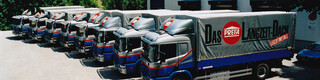 Osem bývalých nákladných áut PREFA v modrej a striebornej farbe s logom PREFA pekne v jednom rade 