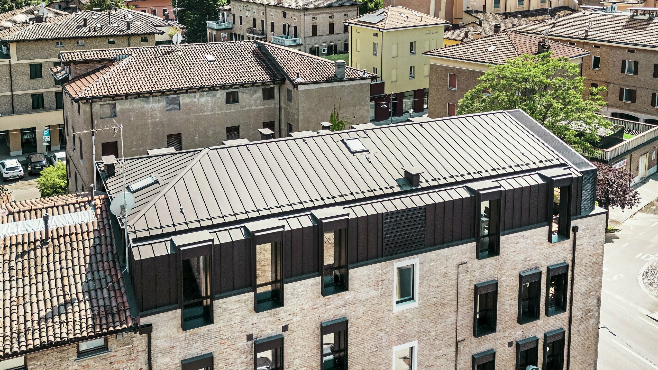 Modernizovaný tehlový dom v Taliansku s hliníkovou strechou PREFALZ v farbe P.10 orieškovohnedá – estetické spojenie tradičnej tehlovej architektúry a moderného, odolného strešného riešenia.