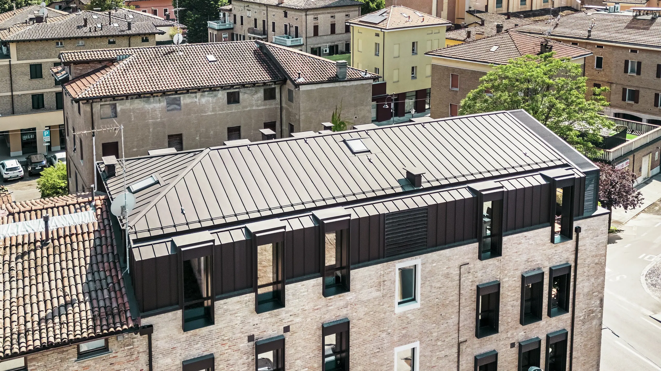 Modernizovaný tehlový dom v Taliansku s hliníkovou strechou PREFALZ v farbe P.10 orieškovohnedá – estetické spojenie tradičnej tehlovej architektúry a moderného, odolného strešného riešenia.