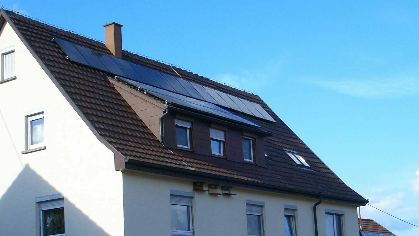 Rodinný dom so strechou z pálenej škridle, ktorá potrebuje rekonštrukciu; na streche je vikier a fotovoltaický systém.