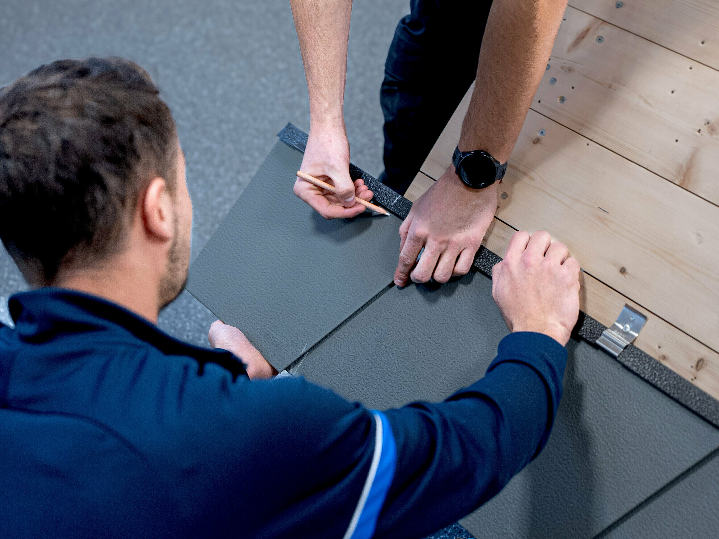 Školiteľ PREFA ukazuje účastníkovi kurzu v stredisku PREFA Academy, ako správne pokladať výrobky PREFA.