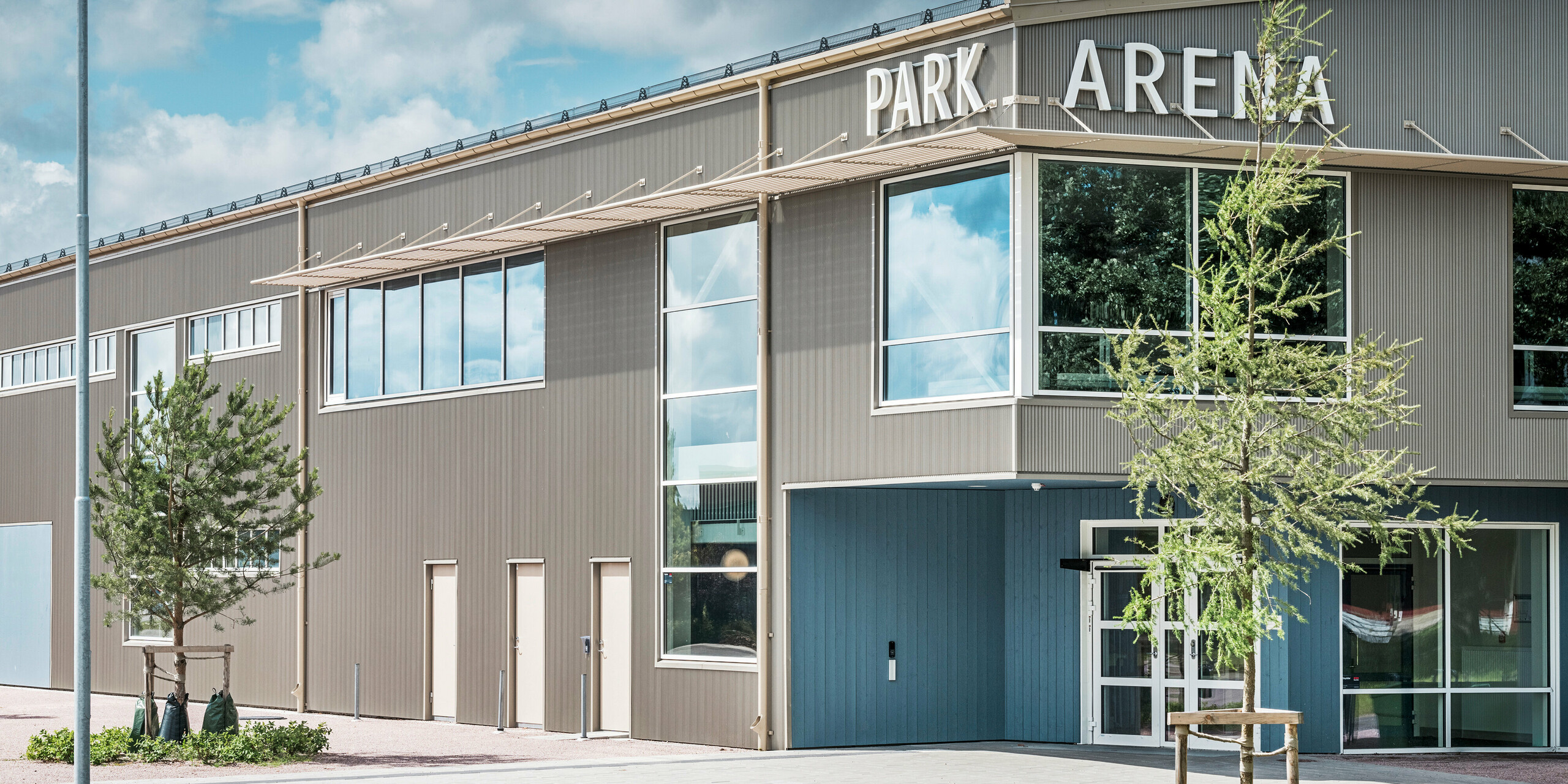 Vstupná časť Park Areny vo švédskom meste Värnamo s moderným dizajnom fasády v podobe prelamovaného profilu PREFA v bronzovej farbe. Trvanlivá hliníková fasáda odolná voči poveternostným vplyvom dodáva športovej hale s rozlohou 3 300 m² elegantný a výrazný vzhľad. Prelamovaný profil PREFA vytvára fascinujúce svetelné a tieňové efekty, ktoré zdôrazňujú architektonický dizajn arény.