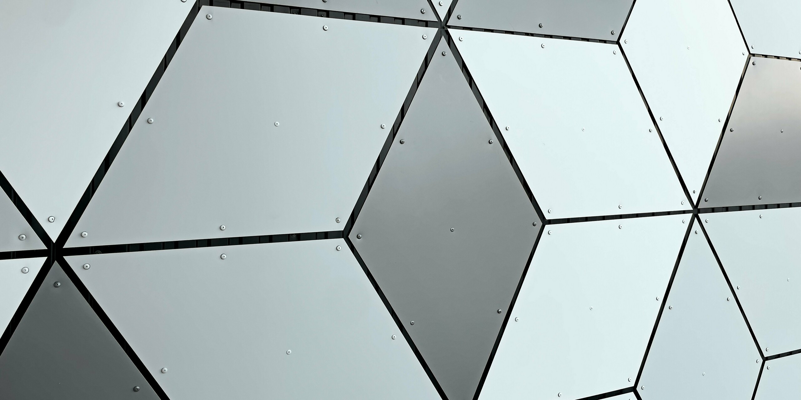 Detail fasády stanice lanovky v Les Deux Alpes. Hliníkové kompozitné panely PREFABOND sú usporiadané do tvaru diamantu. Fascinujúca kombinácia bielych a sivých tónov vytvára moderný geometrický vzor. Pevné upevnenie pomocou skrutiek zdôrazňuje trvanlivú a odolnú konštrukciu, ktorá odolá extrémnym poveternostným podmienkam vo vysokých horách.