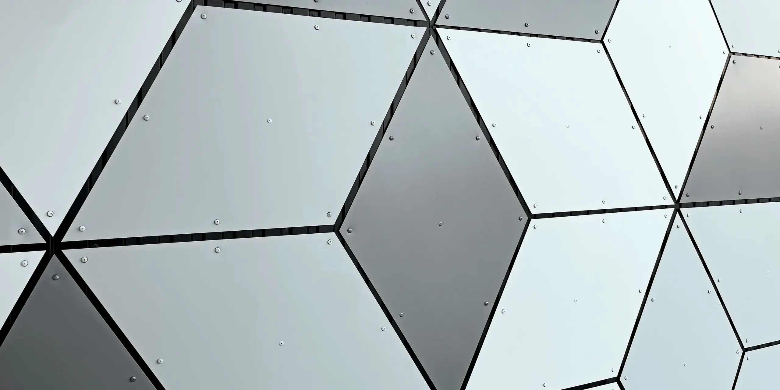 Detail fasády stanice lanovky v Les Deux Alpes. Hliníkové kompozitné panely PREFABOND sú usporiadané do tvaru diamantu. Fascinujúca kombinácia bielych a sivých tónov vytvára moderný geometrický vzor. Pevné upevnenie pomocou skrutiek zdôrazňuje trvanlivú a odolnú konštrukciu, ktorá odolá extrémnym poveternostným podmienkam vo vysokých horách.