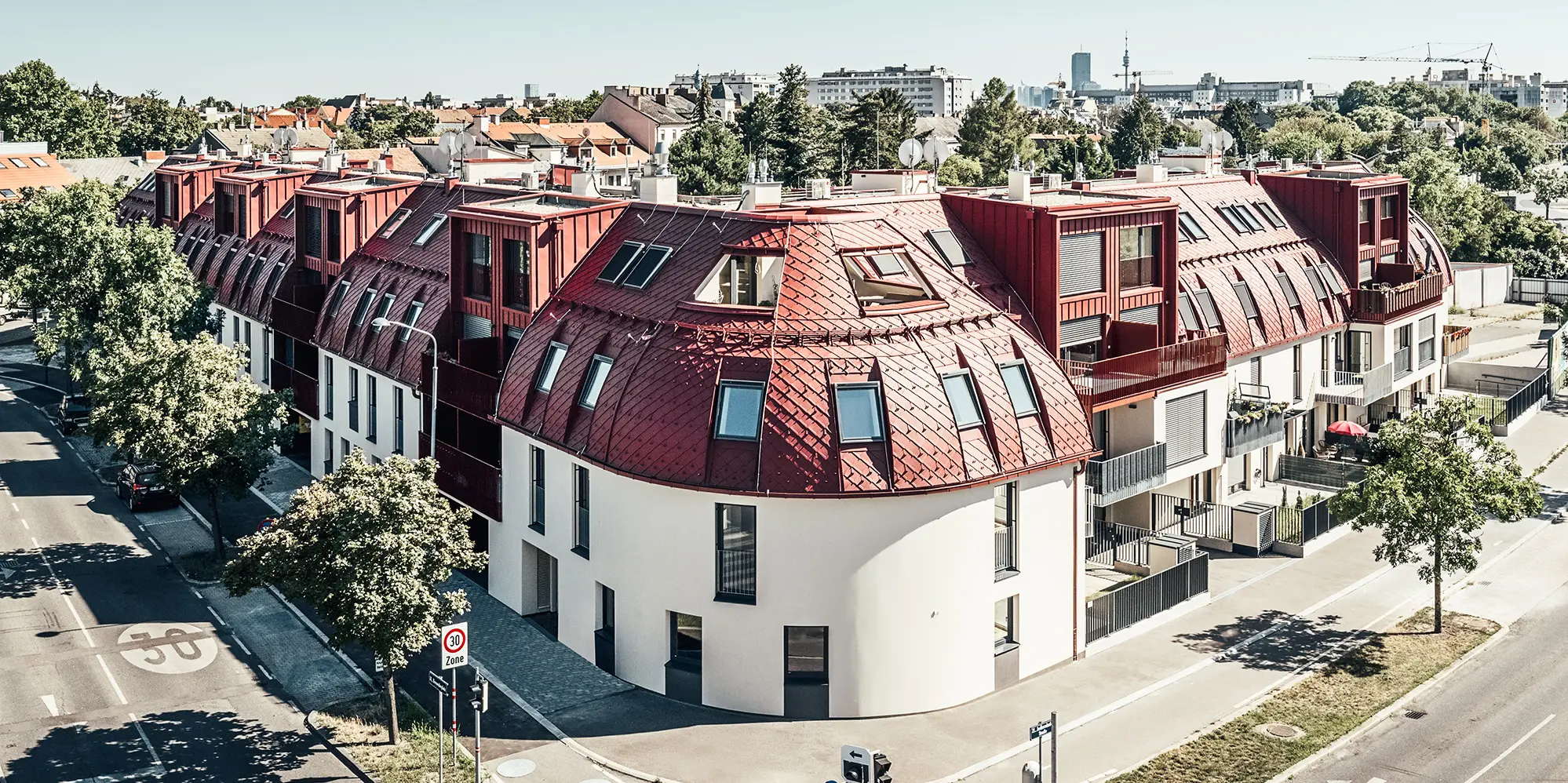 Pohľad na obytný komplex Schöneck 13 a zaoblenú strešnú krajinu, navrhnutú architektonickým ateliérom schneider+schumacher.