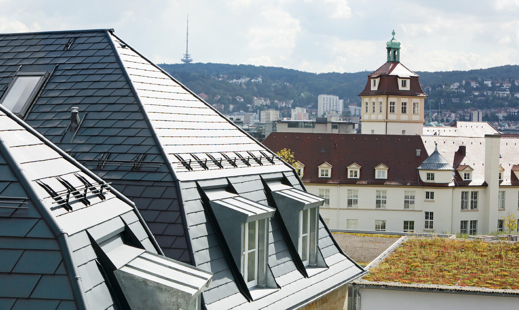 Starý mestský dom v Stuttgarte so zalomenou strechou a mnohými oknami vo vikieroch, pokrytá hliníkovým šindľom od spoločnosti PREFA vo farbe P.10 antracitová