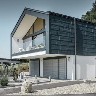 Moderný bytový dom pre viacero rodín s veľkým presklenným priečelím, strecha a fasáda boli odeté do fasádneho panelu PREFA FX.12 v antracitovej farbe
