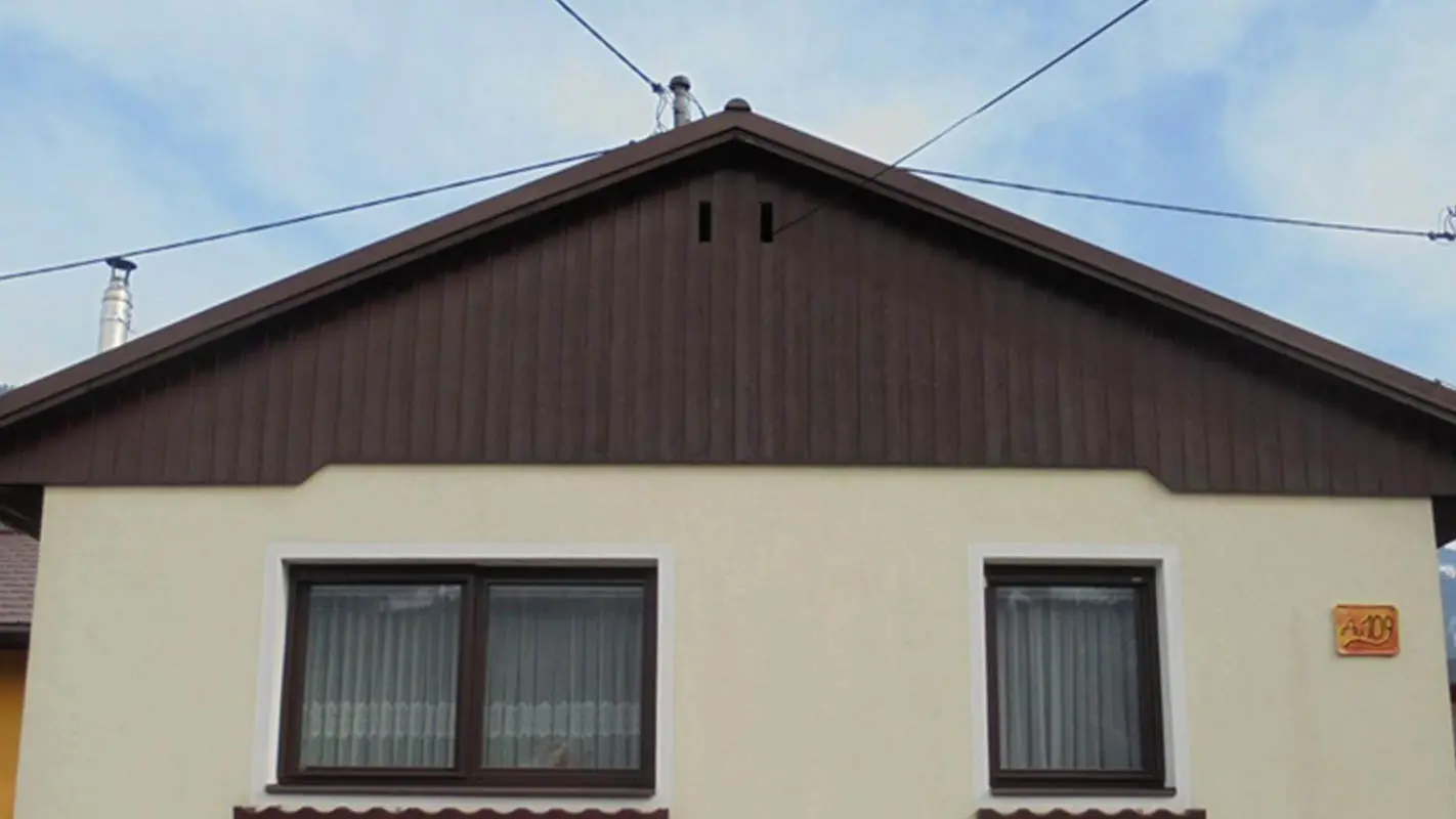 Stav pred rekonštrukciou fasády štítu s použitím PREFA Sidings, žltá omietková fasáda, zvetrané drevo