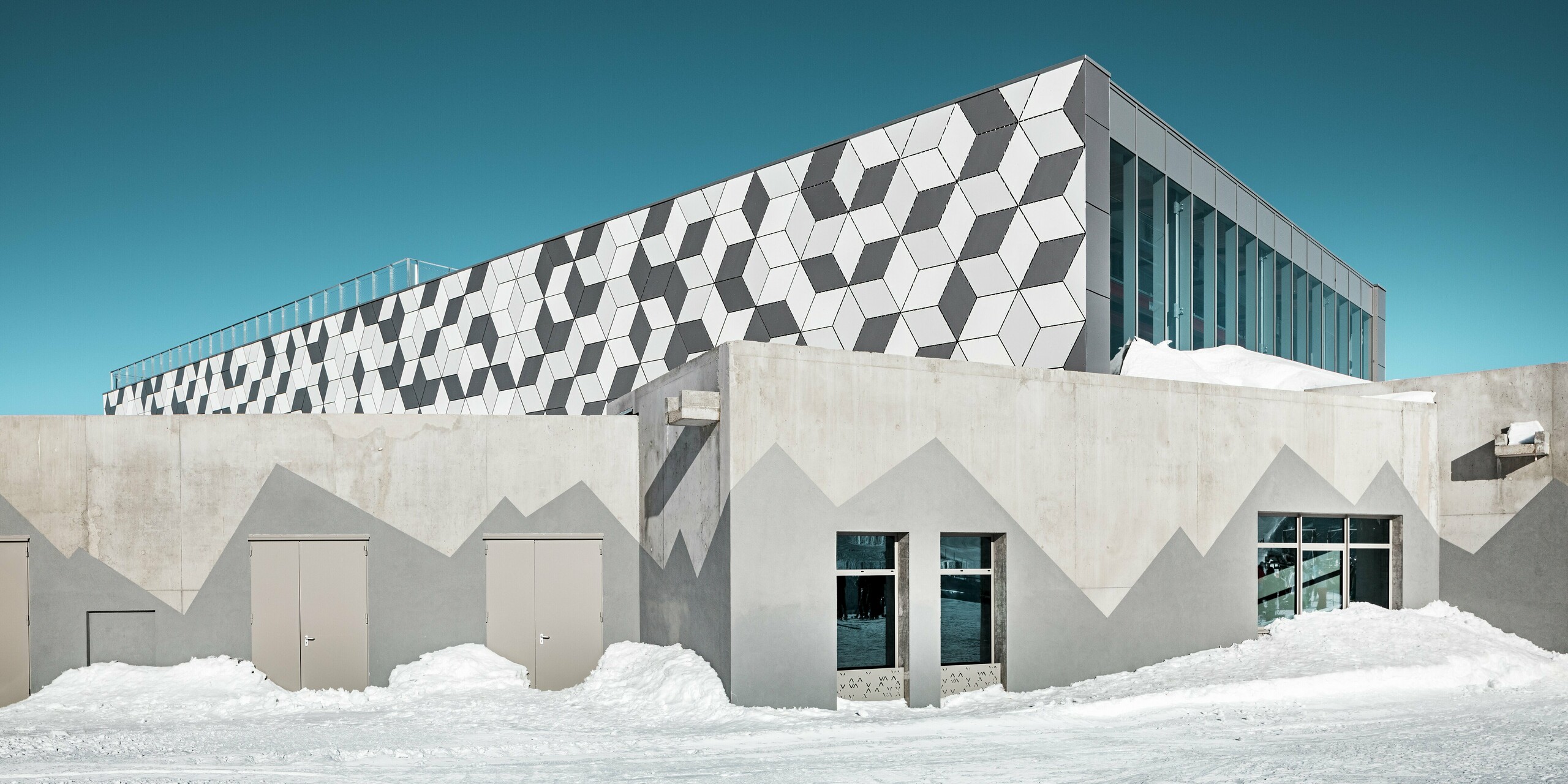 Moderná horská stanica lanovky 3S v Les Deux Alpes žiari futuristickou fasádou z hliníkových kompozitných panelov PREFABOND s pútavým kosoštvorcovým vzorom. Farby P.10 prefa biela, P.10 čistá biela a dymová strieborná vytvárajú fascinujúci 3D vzor, ktorý dokonale ladí so zasneženou vysokohorskou krajinou. Fasáda je odolná voči poveternostným vplyvom, trvácna a predstavuje skutočný estetický vrchol. Spodná časť budovy je vyrobená z pohľadového betónu. Na imitáciu hôr bola použitá tmavosivá farba.