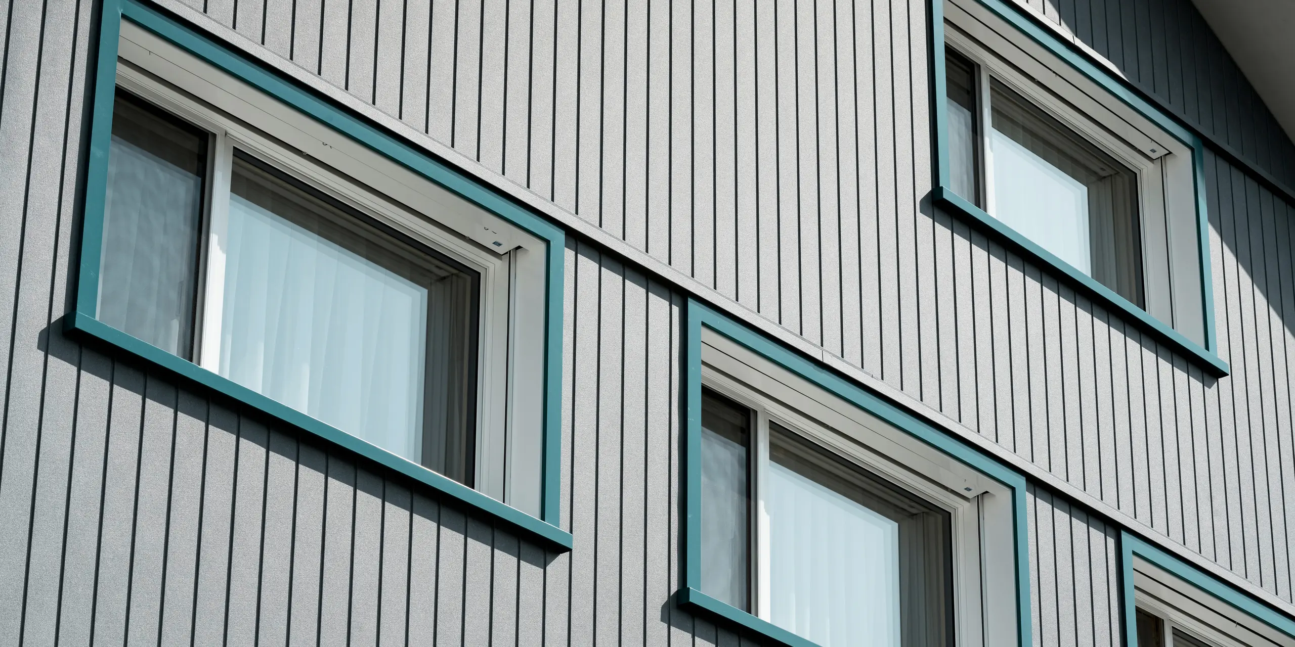 PREFA Siding vo farbe P.10 kamenná šedá a P.10 prefa biela na fasádach dvoch susedných bytových domov vo Weissbad vo Švajčiarsku.