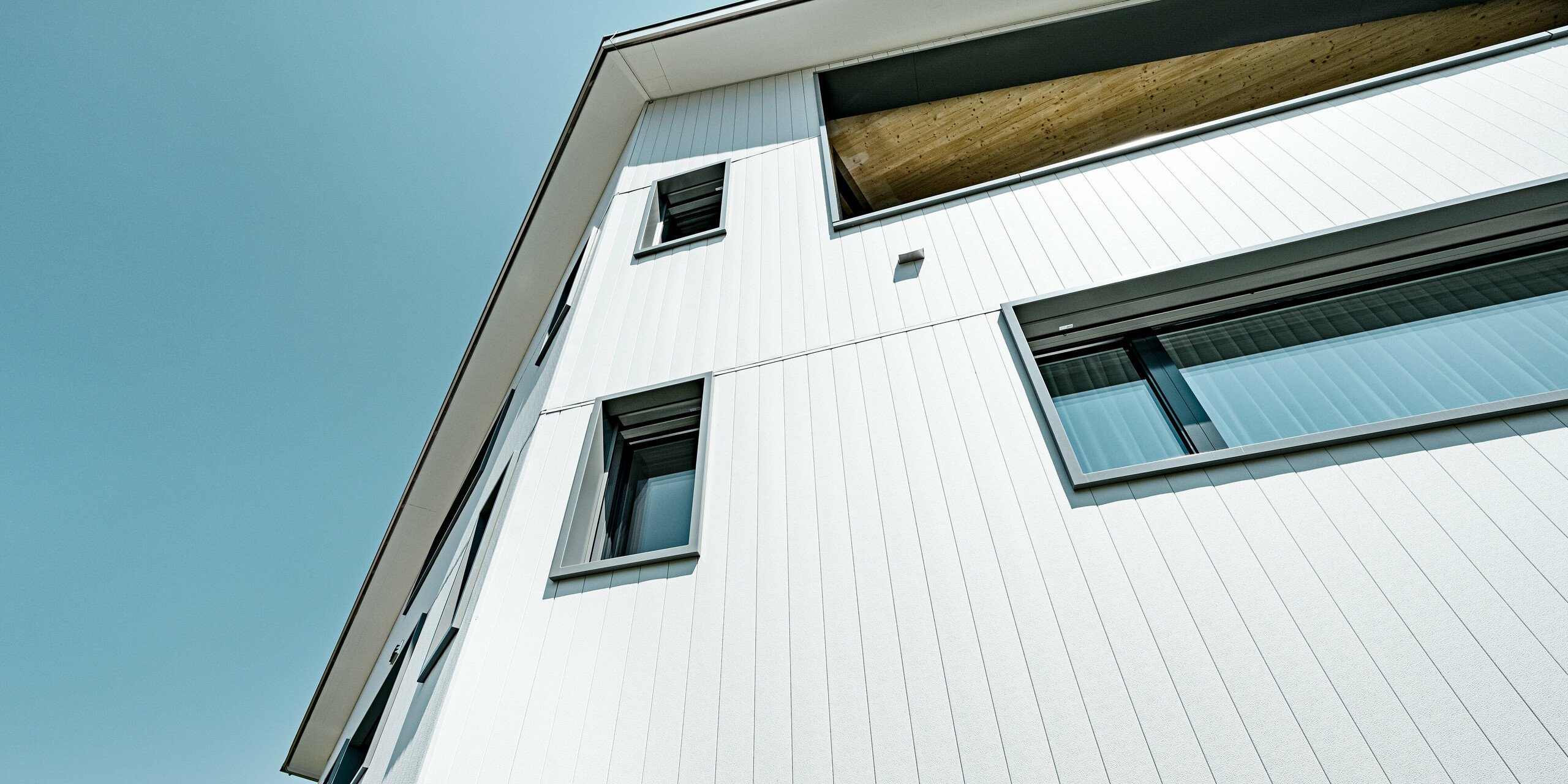 PREFA Siding vo farbe P.10 kamenná šedá a P.10 prefa biela na fasádach dvoch susedných bytových domov vo Weissbad vo Švajčiarsku.