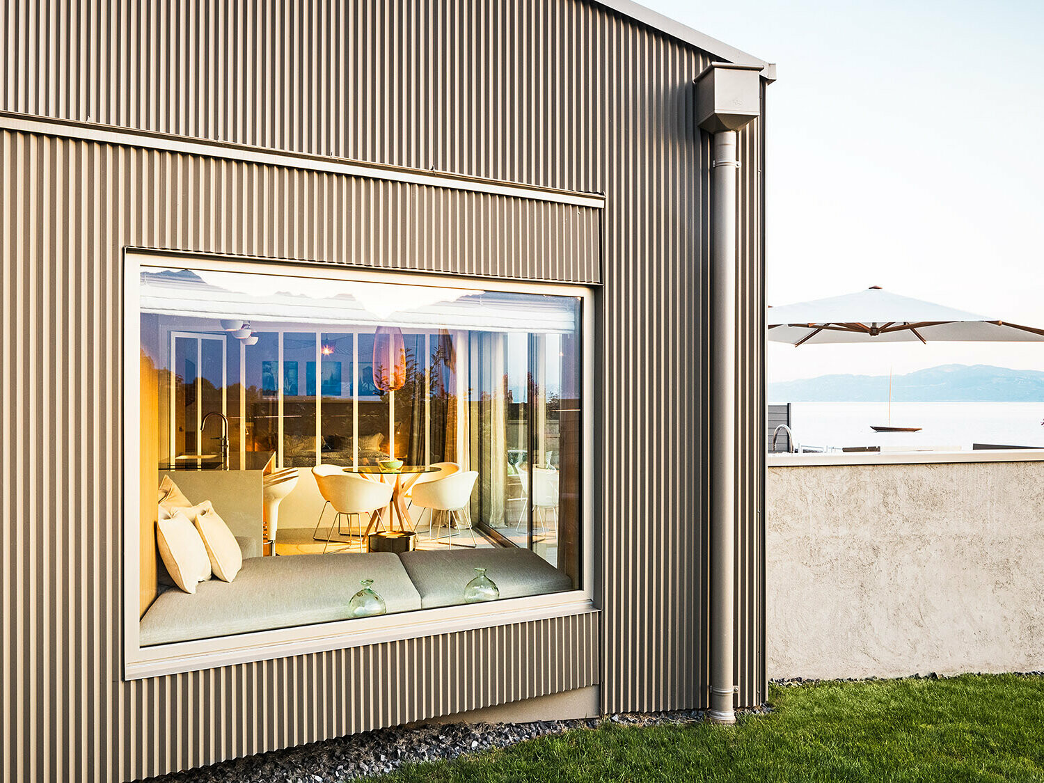 Bočný pohľad na budovu s prelamovanou hliníkovou fasádou, v zábere je vidieť časť osvetleného interiéru.